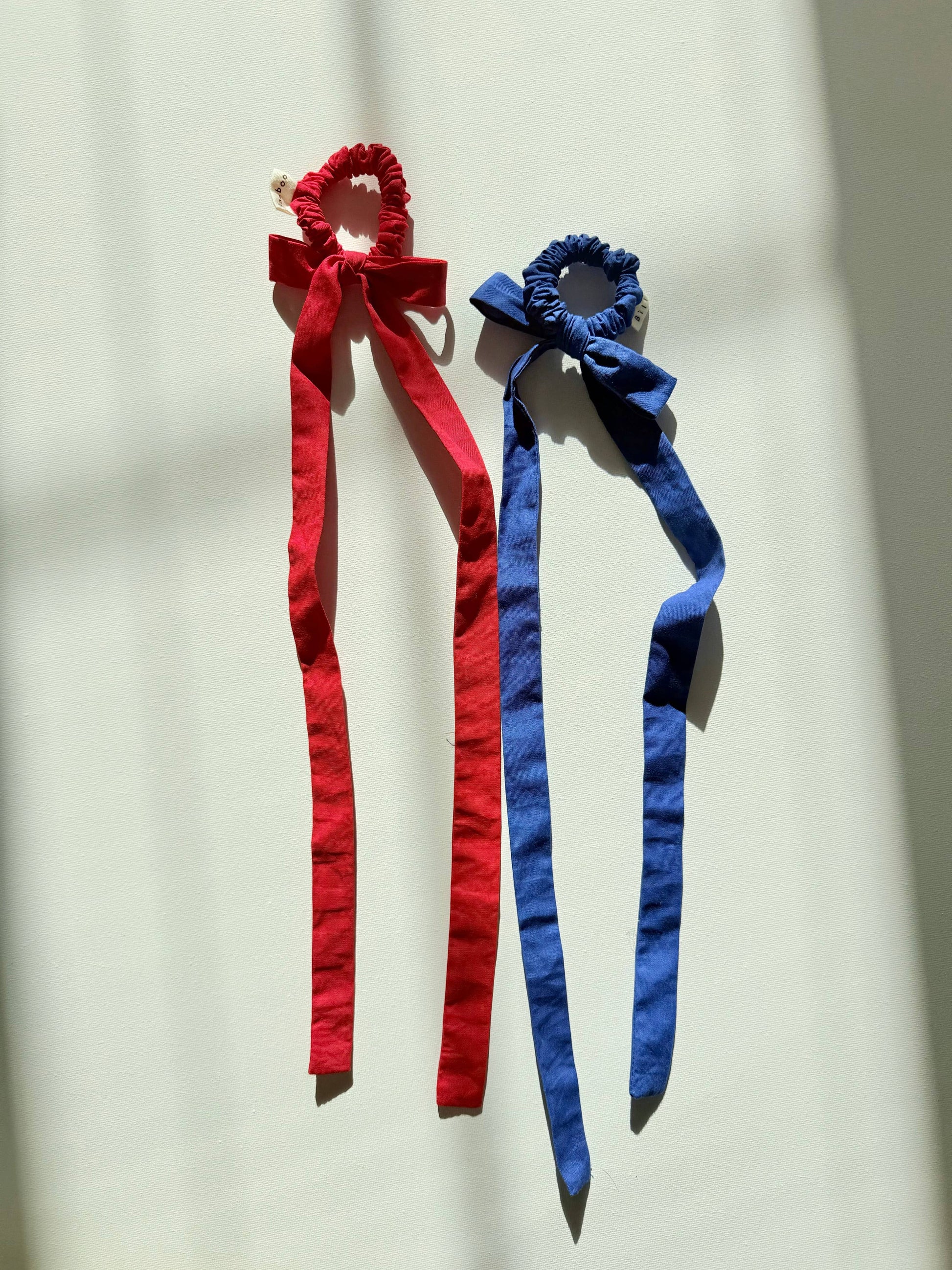 Red and blue hair ties with ribbons on a light background