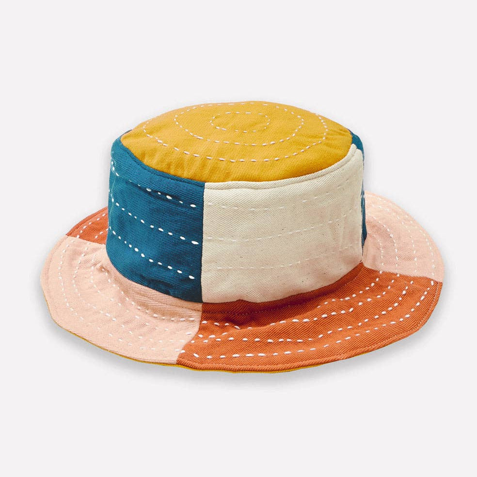 Color-blocked bucket hat with yellow, blue, beige, and orange sections on a white background