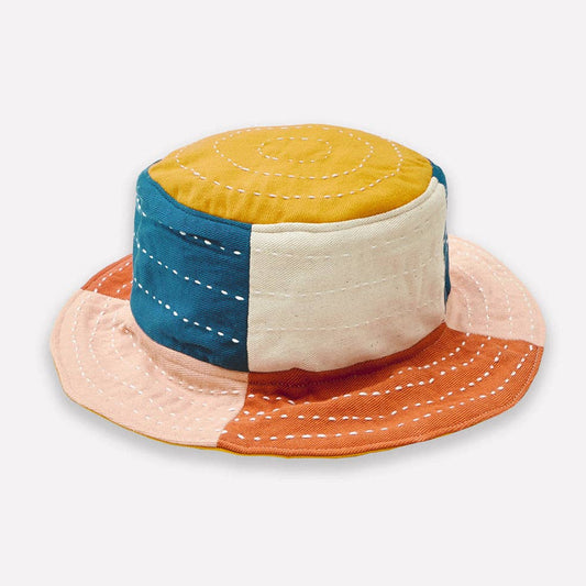 Color-blocked bucket hat with yellow, blue, beige, and orange sections on a white background