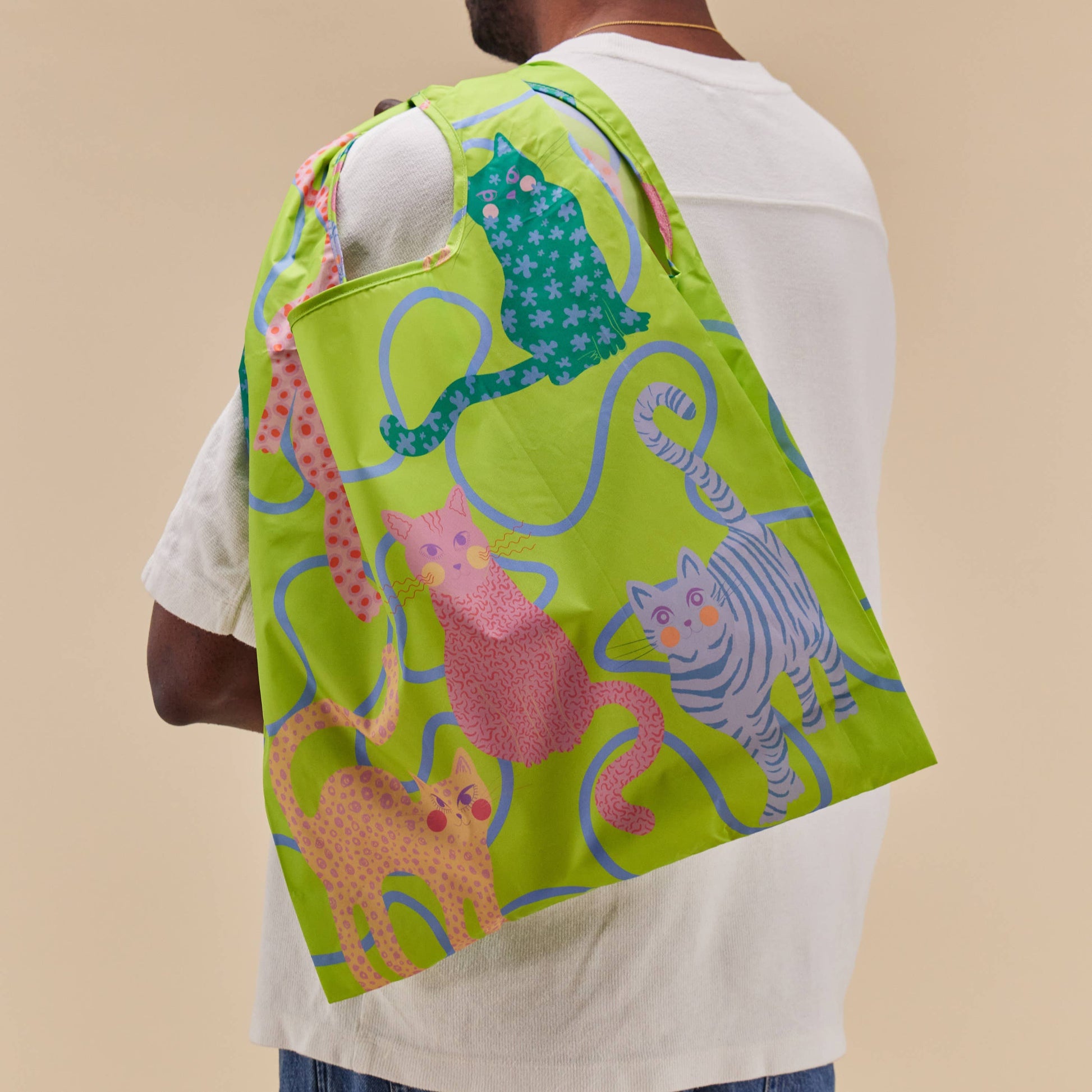 Person wearing a green drawstring bag with animal patterns on a beige background