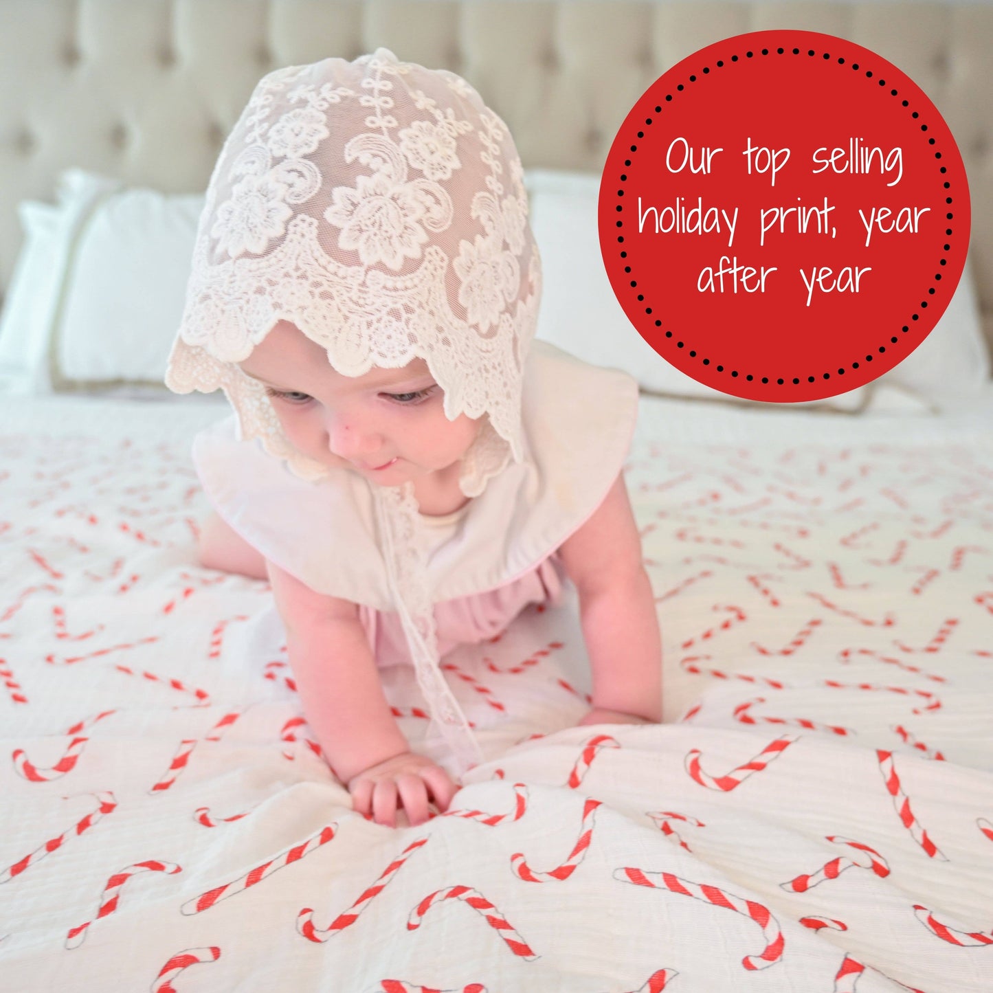 Baby wearing a lace bonnet on a white blanket with red patterns, surrounded by text about top-selling holiday prints.