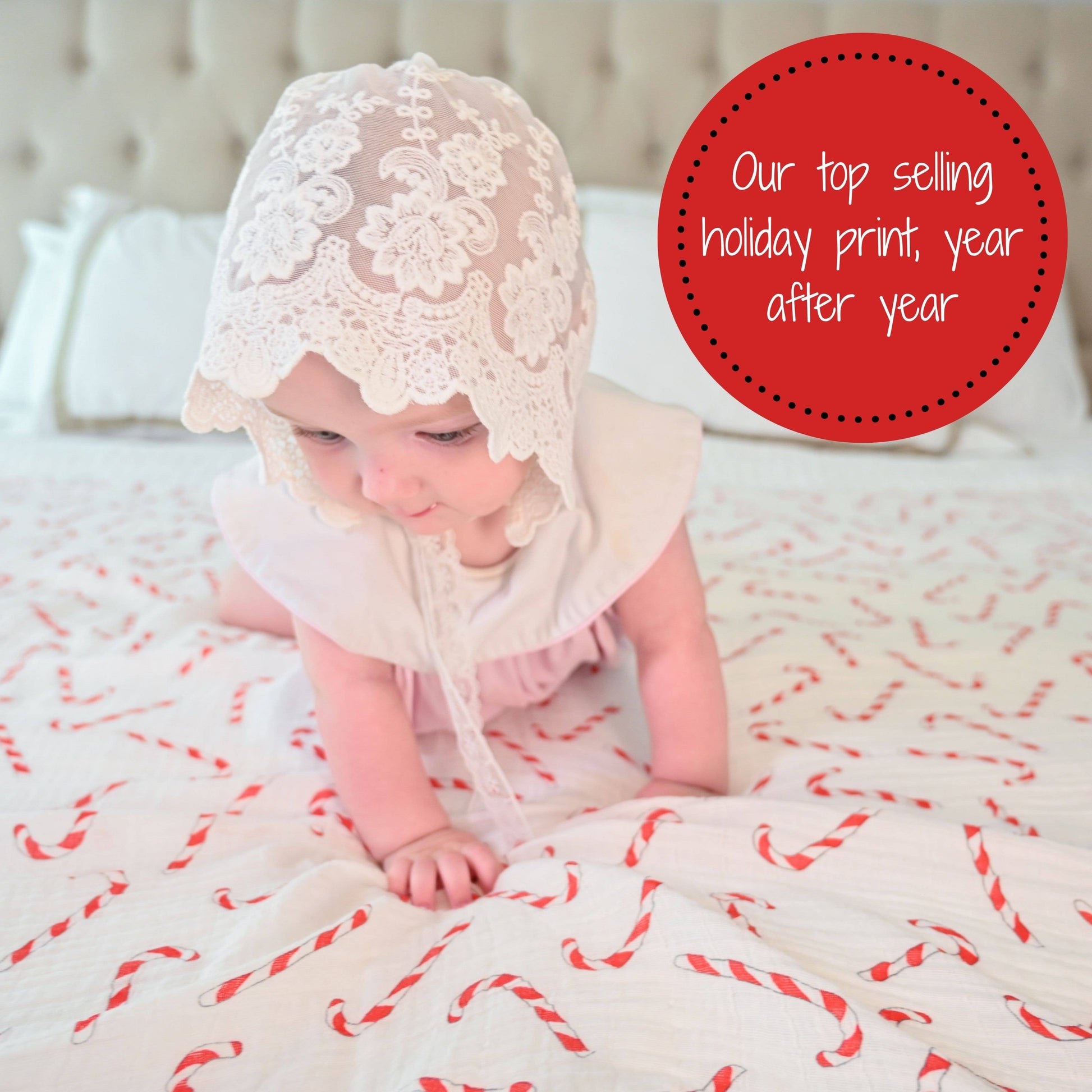 Baby wearing a lace bonnet on a white blanket with red patterns, surrounded by text about top-selling holiday prints.