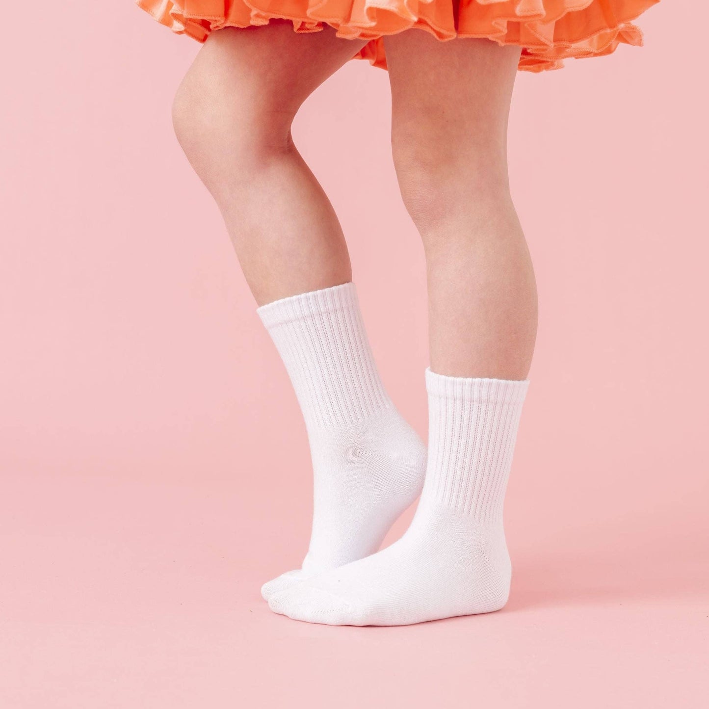 White socks worn with an orange tutu on a pink background