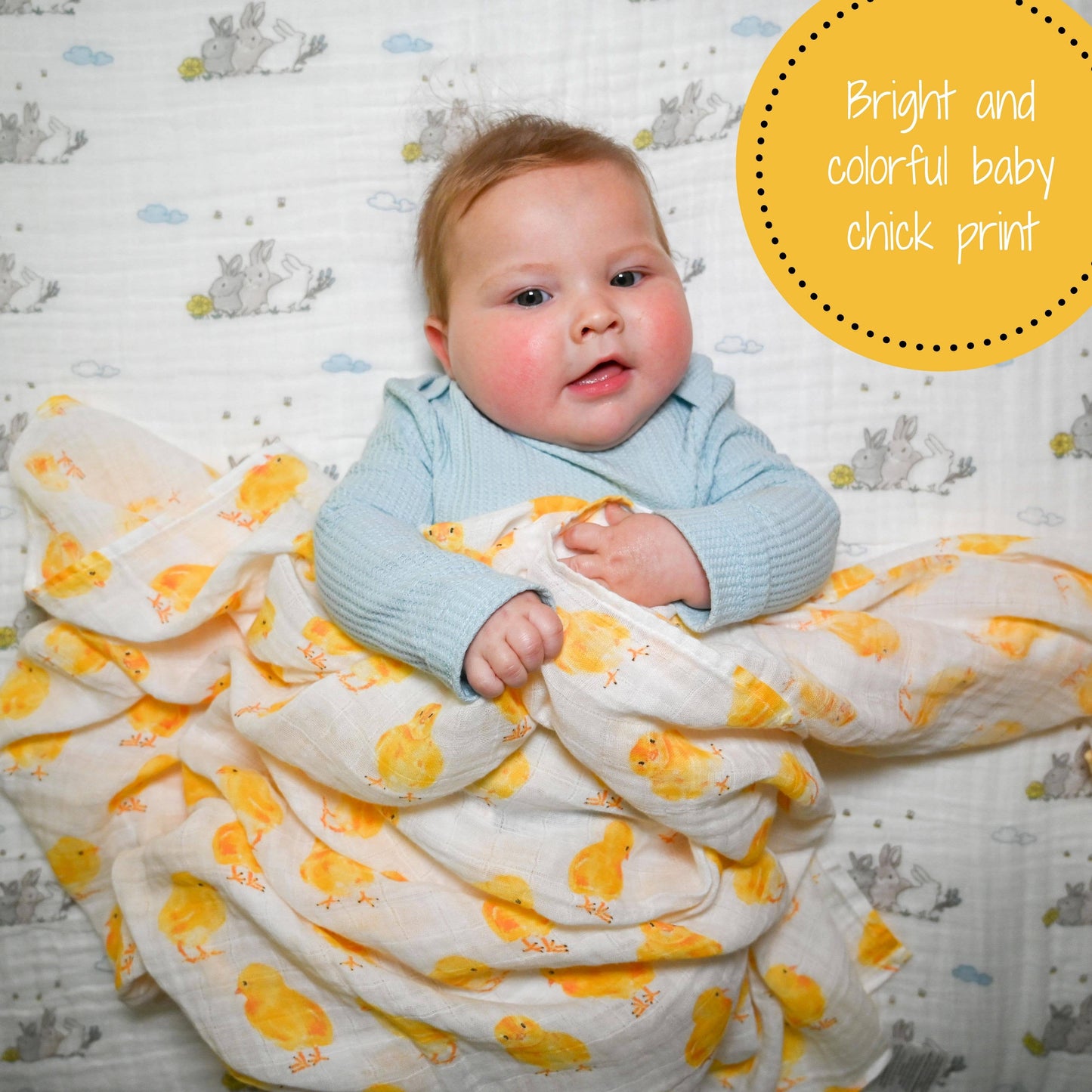Baby wrapped in a yellow and white chick print blanket on a patterned background