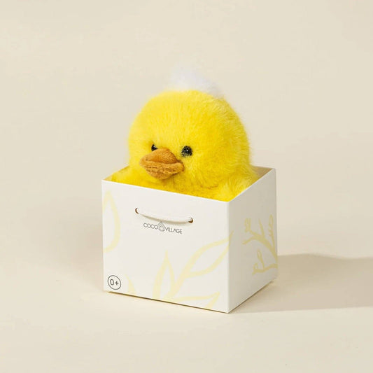 Yellow duck plush toy in a white box on a beige background