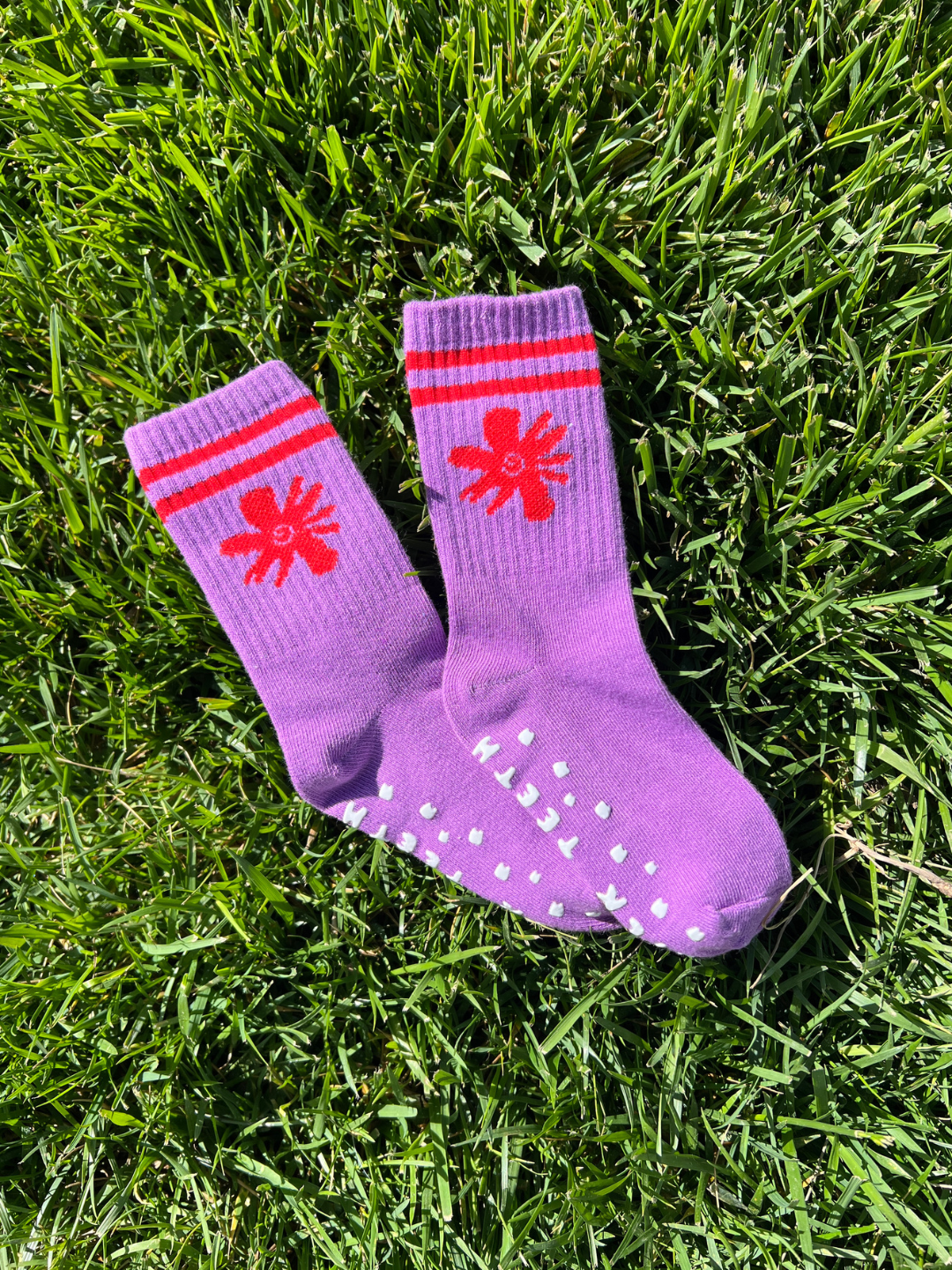 Purple socks with red star designs on grass