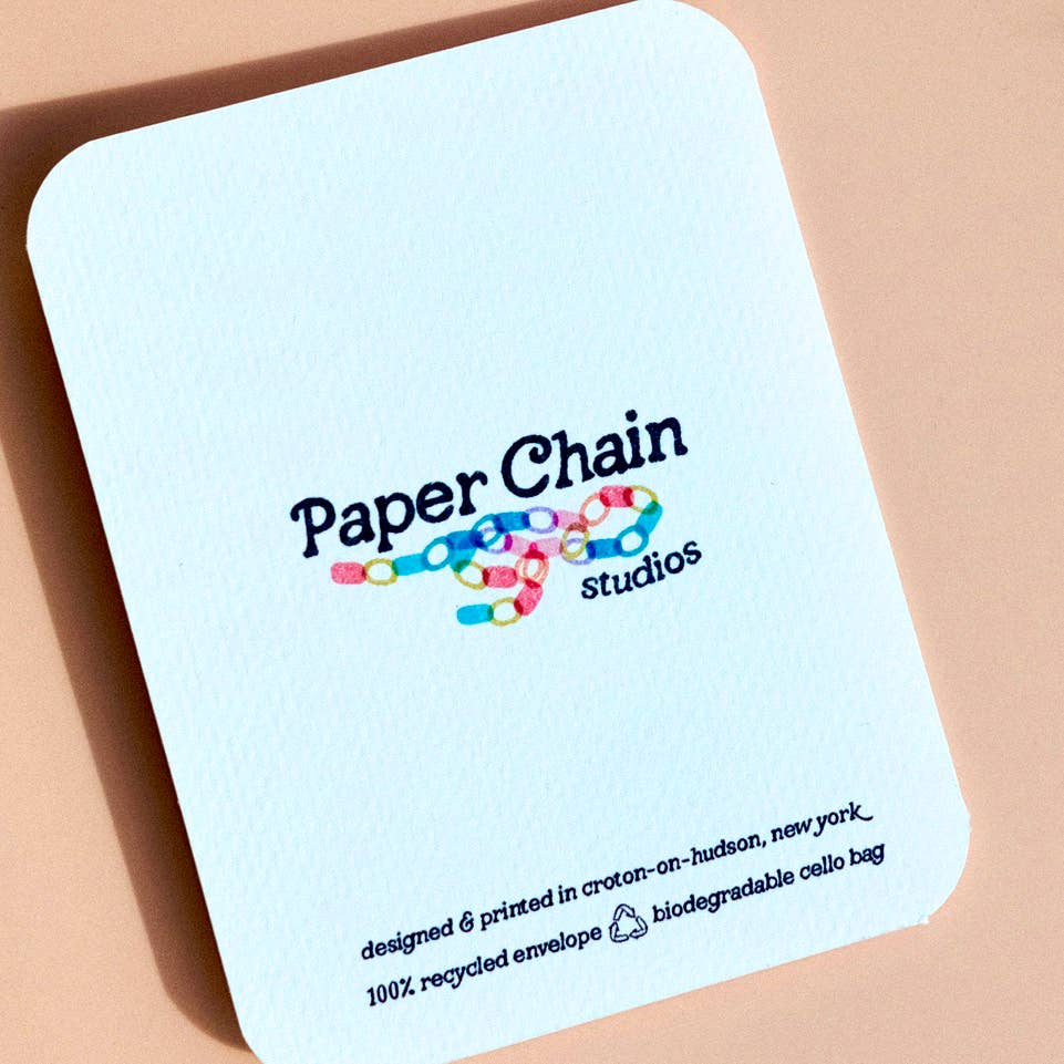 Recycled envelope with 'Paper Chain Studios' branding on a beige background