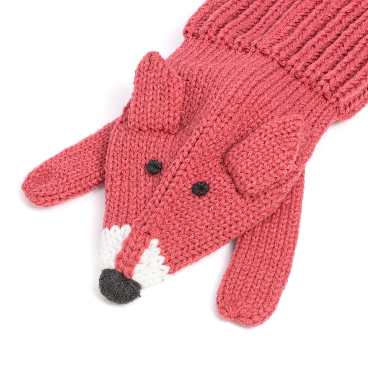 Kknitted fox-themed scarf  in a dusty rose pink color, featuring embroidered black eyes and nose, and a white and black snout detail, shown on a plain white background.