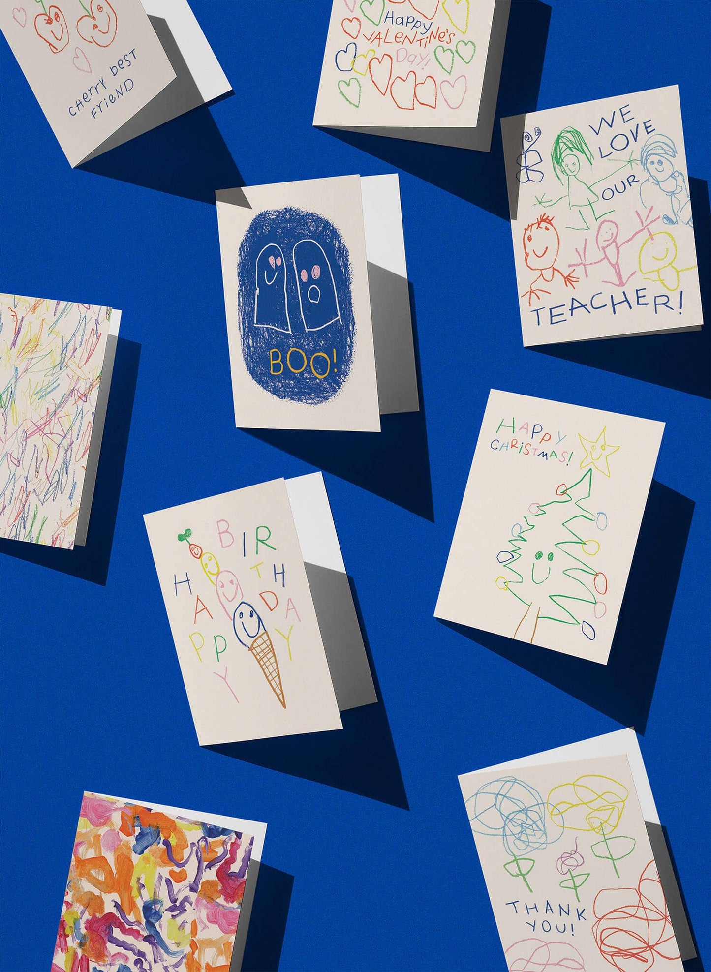 Colorful children's drawings on greeting cards against a blue background