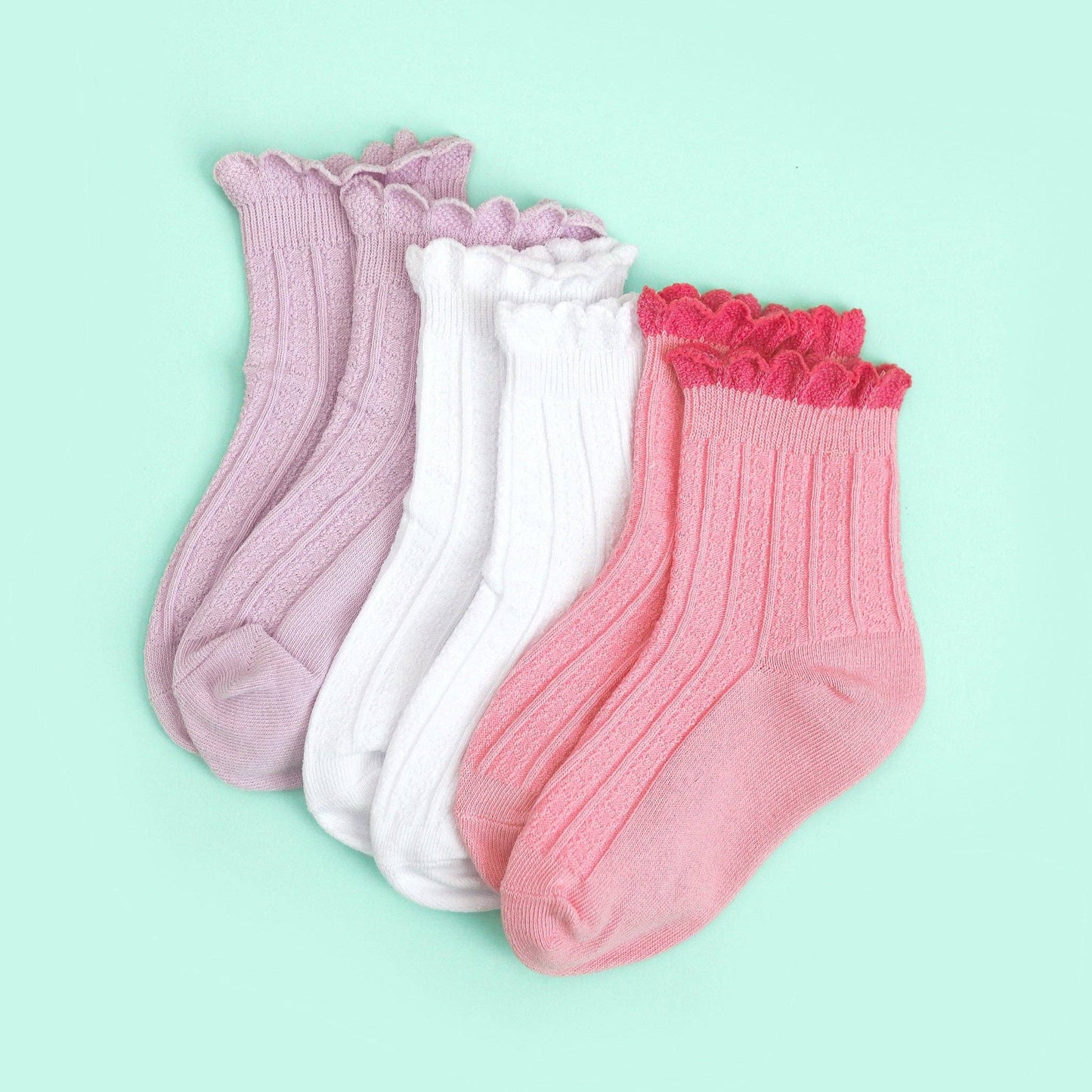 Three pairs of socks with lace trim on a light green background
