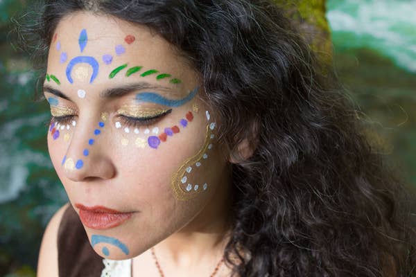 Woman with colorful face paint against a natural background