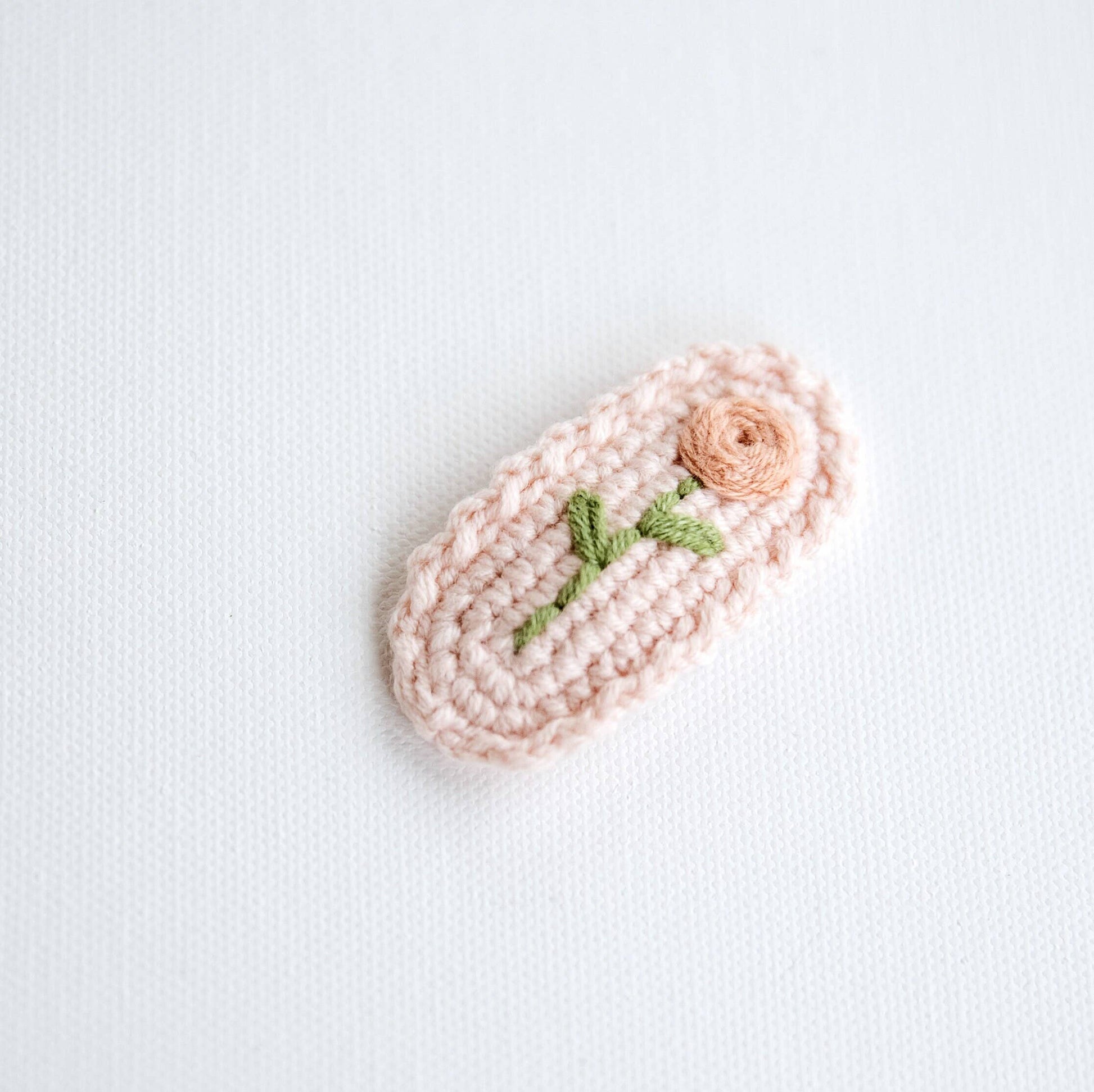 Crocheted item with a flower and leaf design on a light background