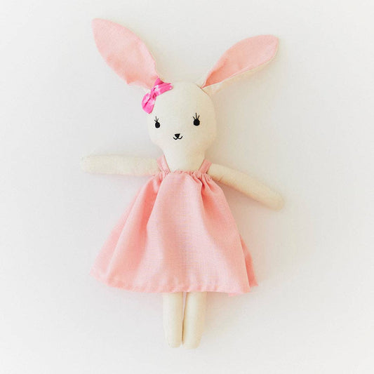 Stuffed bunny toy with a pink dress and bow on a white background