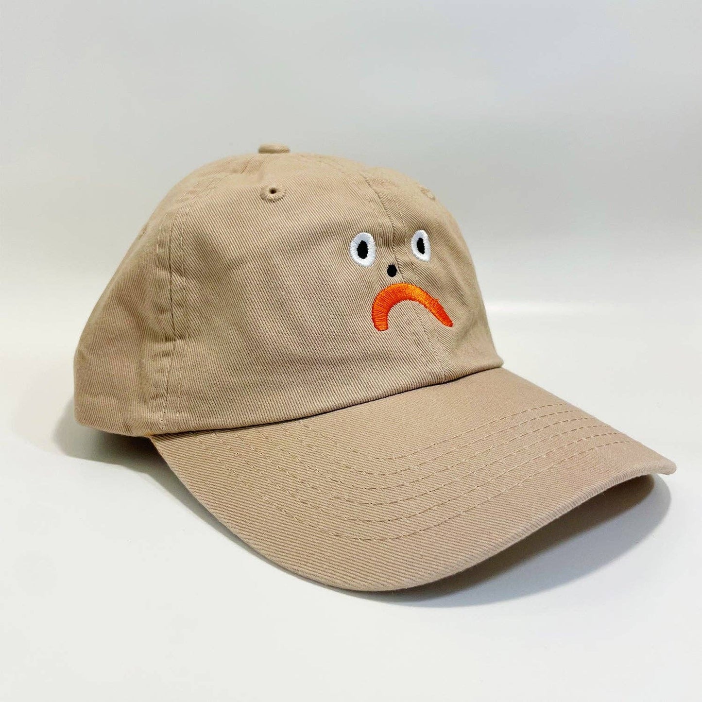 Beige cap with a smiley face design on a white background
