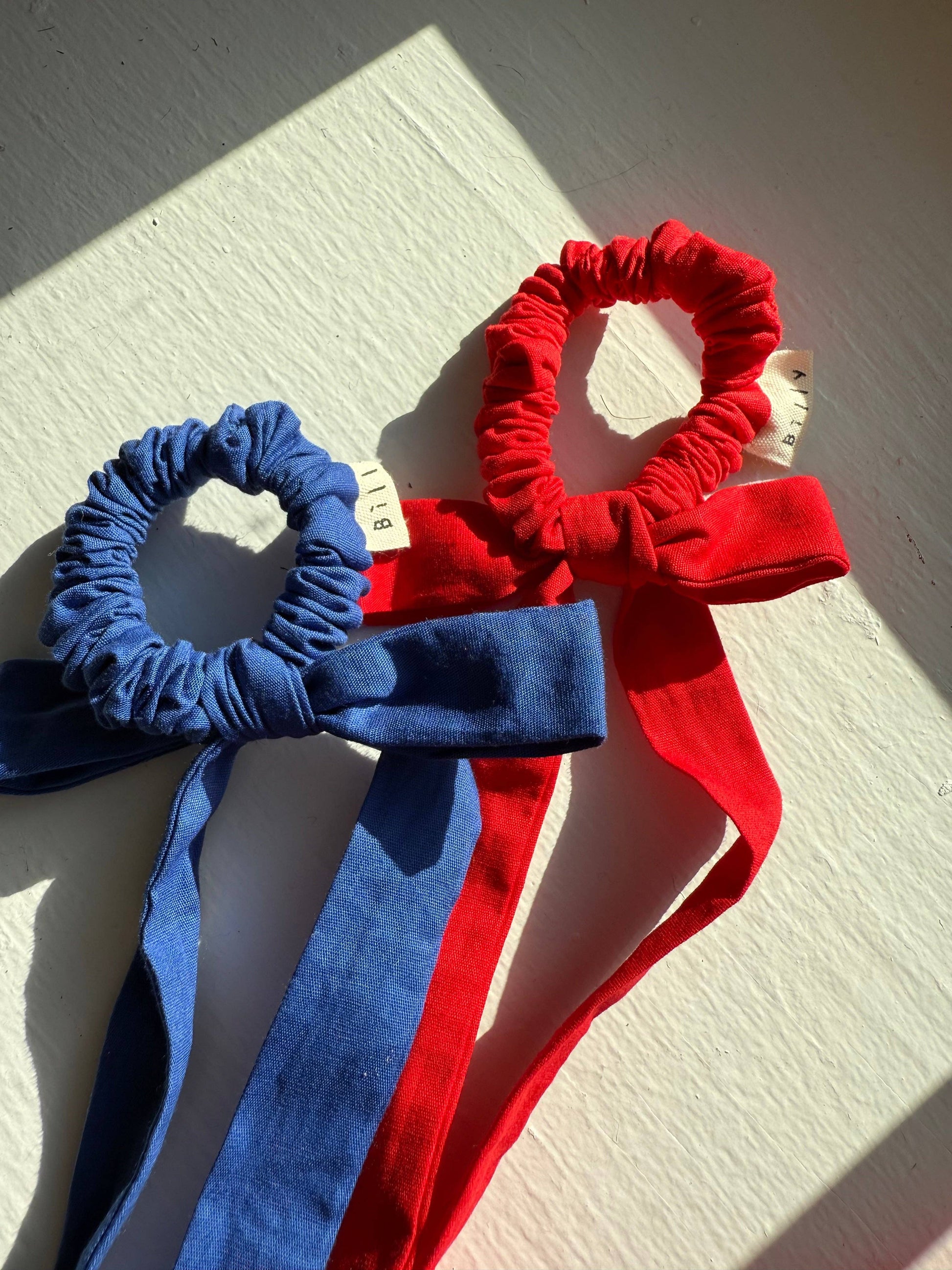 Two hair accessories, one blue and one red, on a light wooden surface.