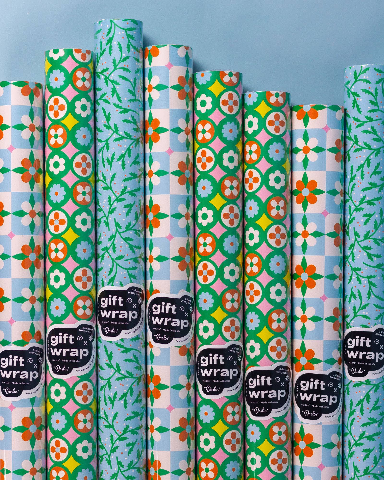 Collection of colorful gift wrap rolls with patterns on a blue background