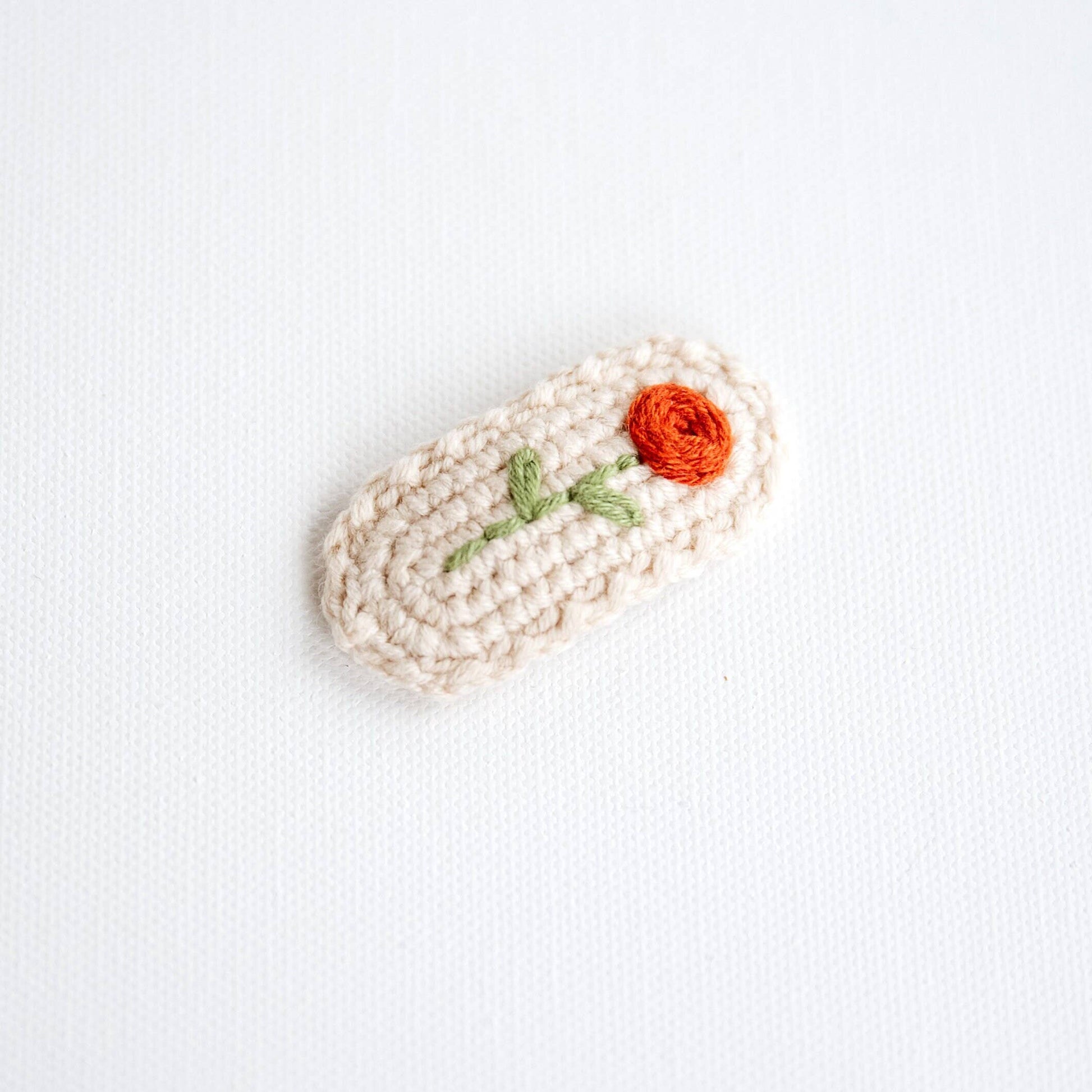 Crocheted item with a red flower on a white background