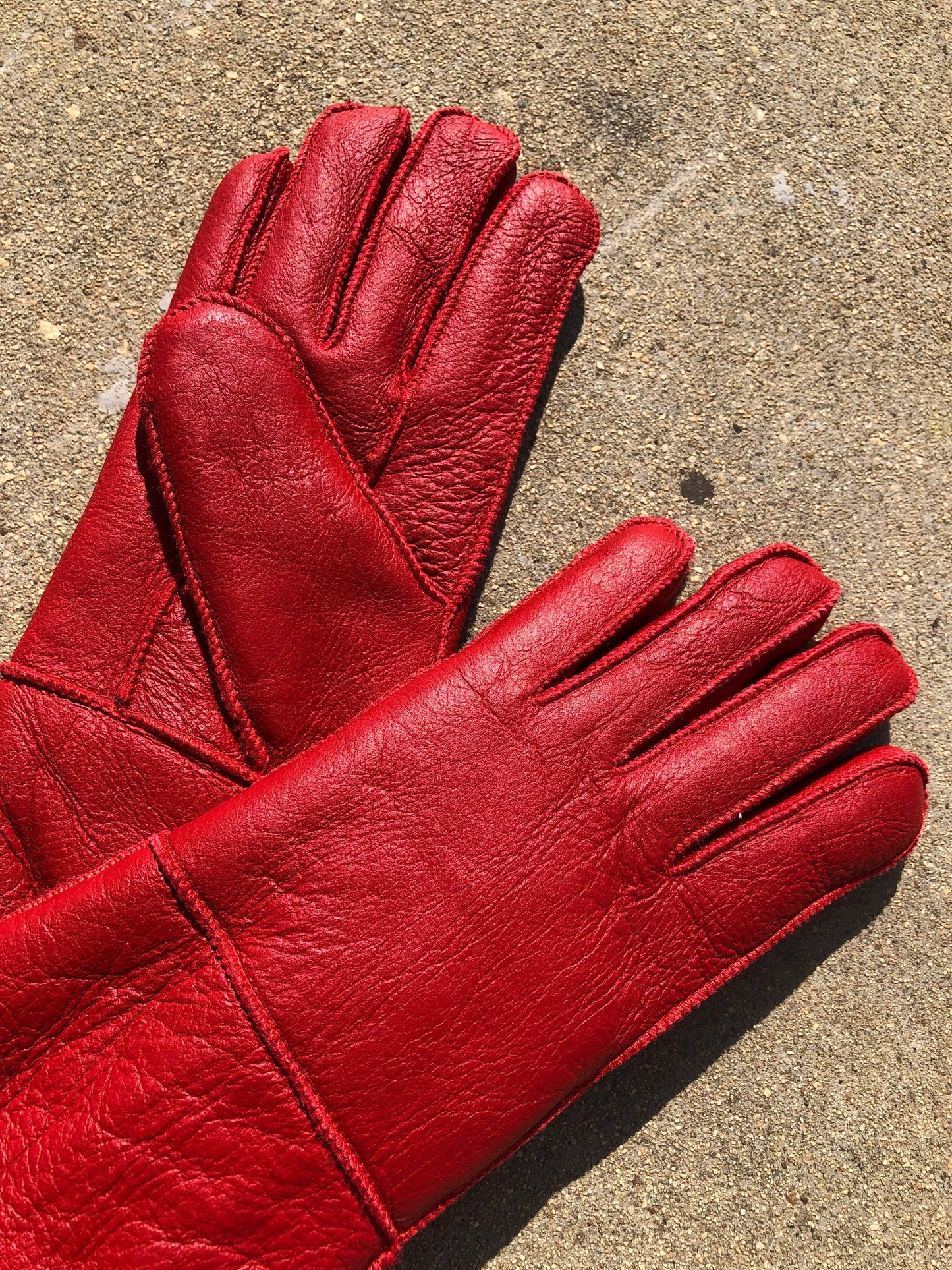 Pair of red leather gloves on a concrete surface
