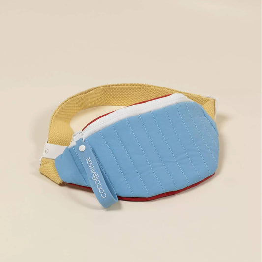 Blue quilted fanny pack on a beige background