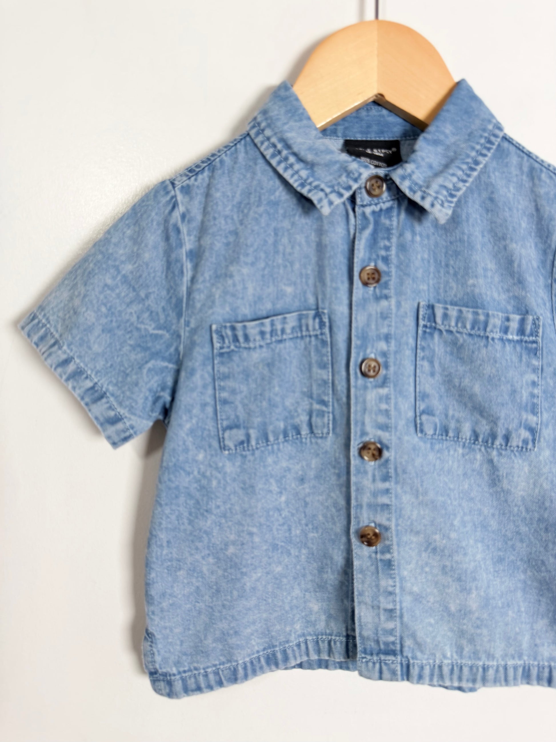 Blue denim shirt on a wooden hanger against a white background