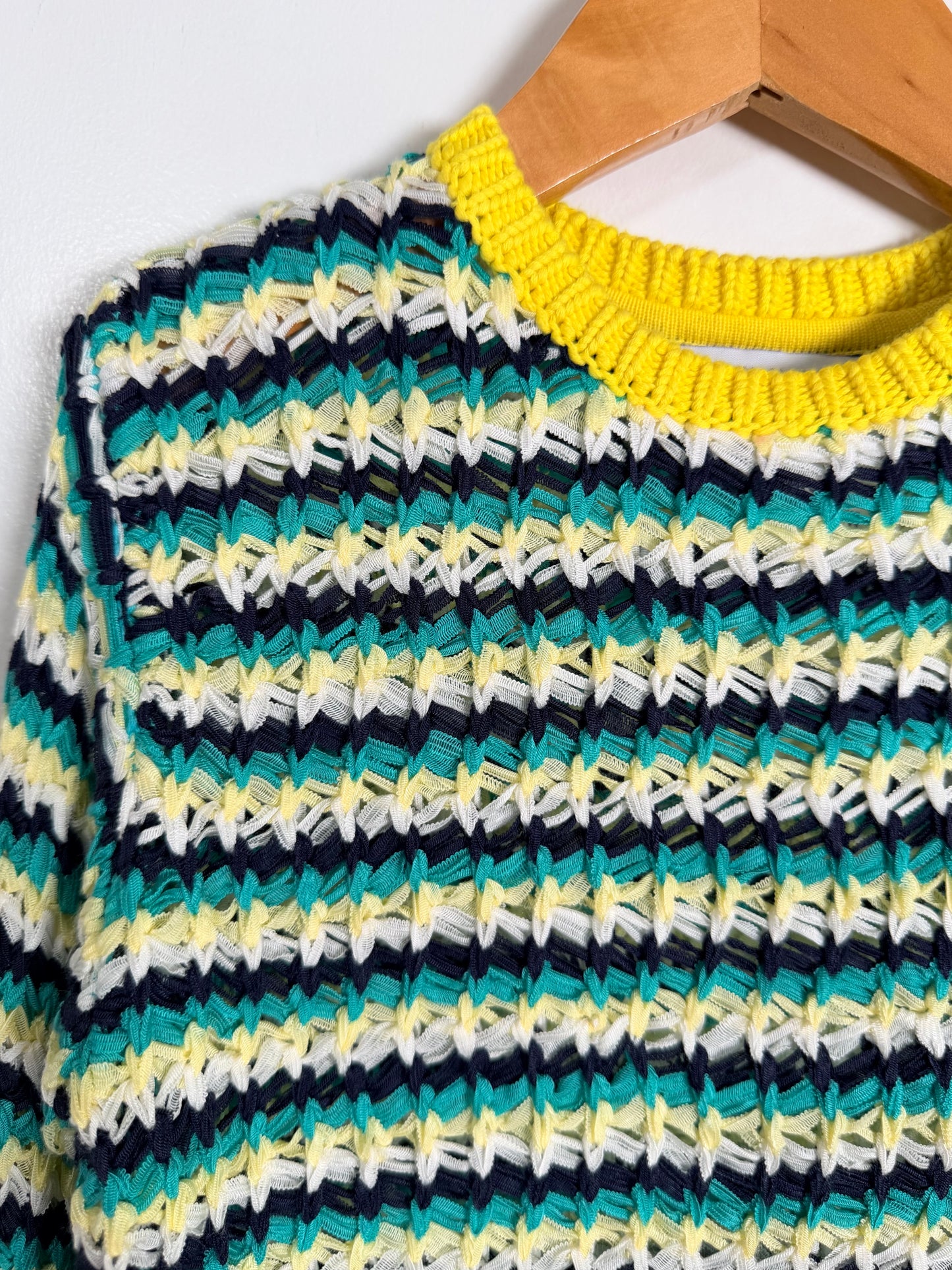 Colorful striped sweater on a hanger against a white background
