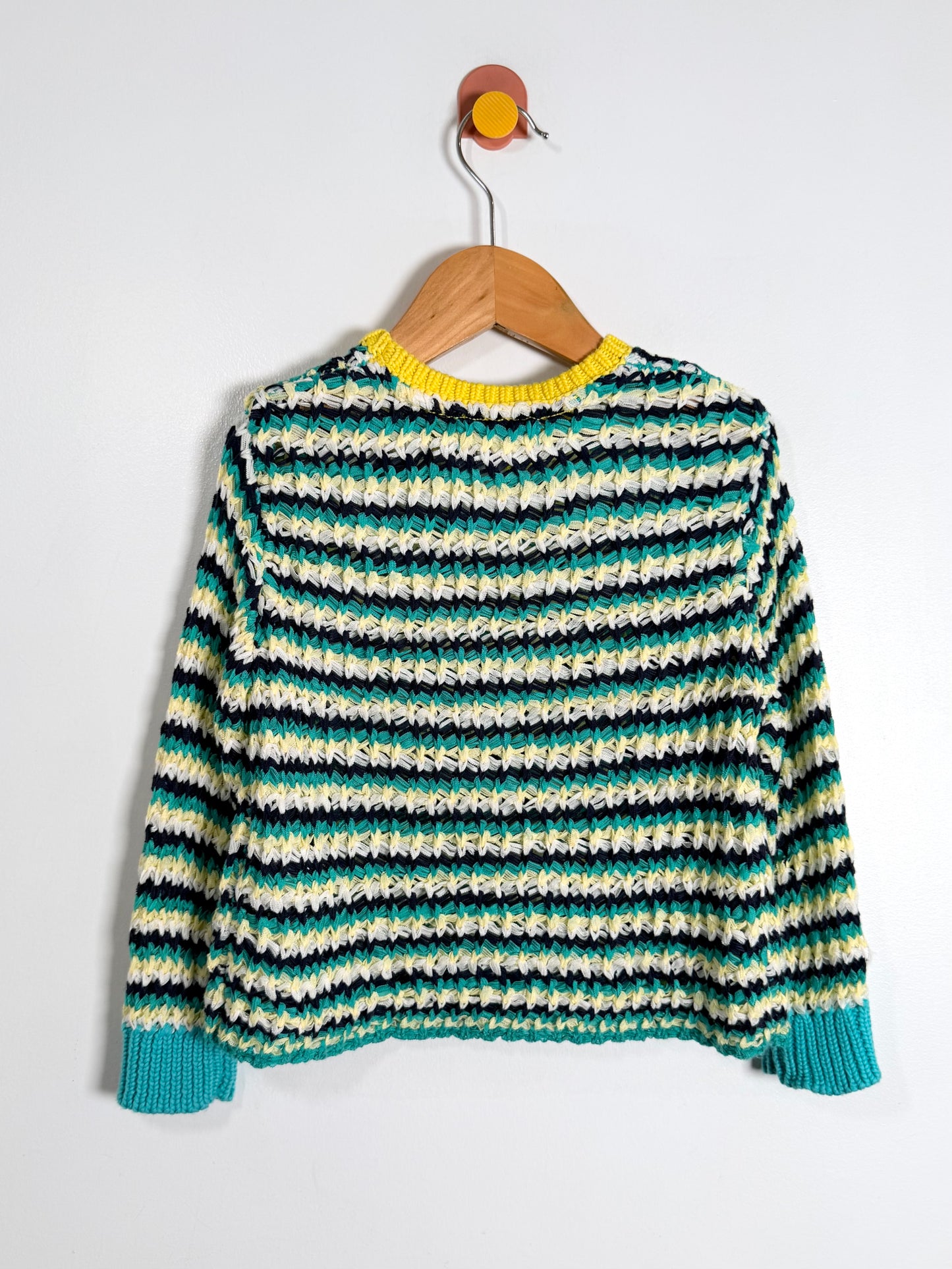 Striped sweater on a wooden hanger against a white background