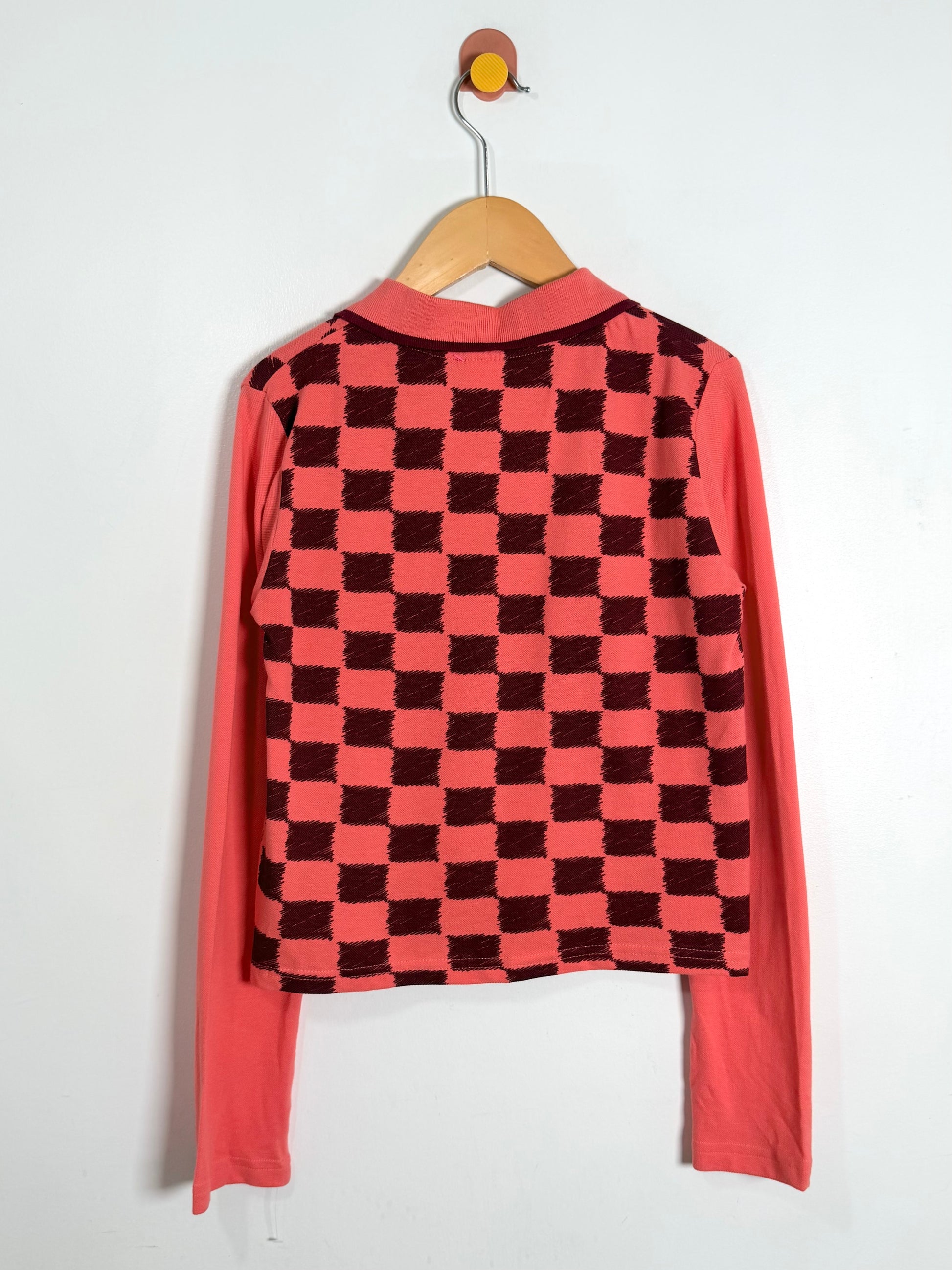 Pink and black checkered shirt on a hanger against a white background