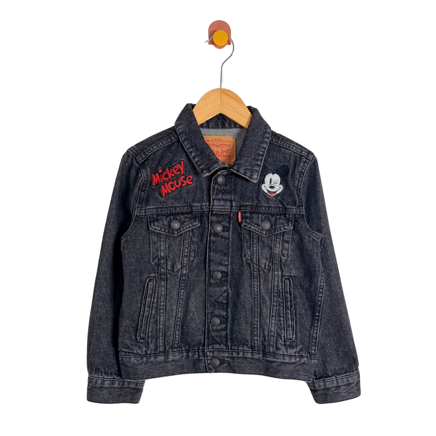 Black denim jacket with Mickey Mouse embroidery on a hanger against a white background
