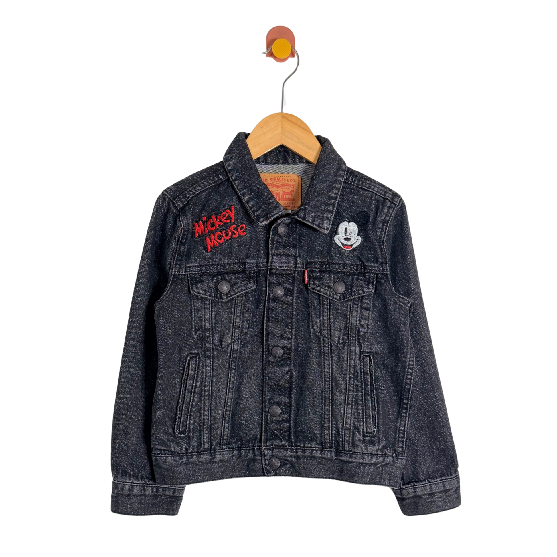 Black denim jacket with Mickey Mouse embroidery on a hanger against a white background