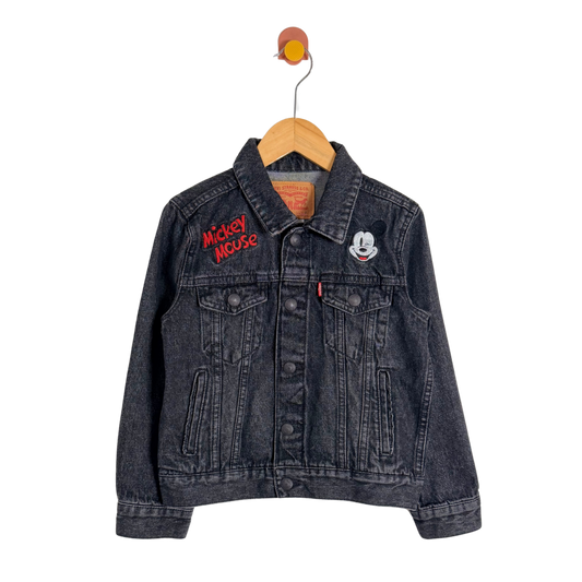 Black denim jacket with Mickey Mouse embroidery on a hanger against a white background