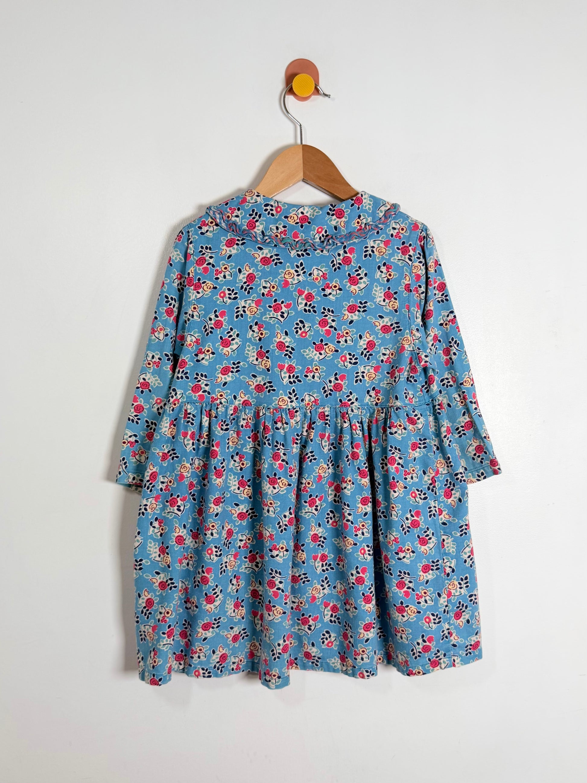 Floral dress on a hanger against a white background