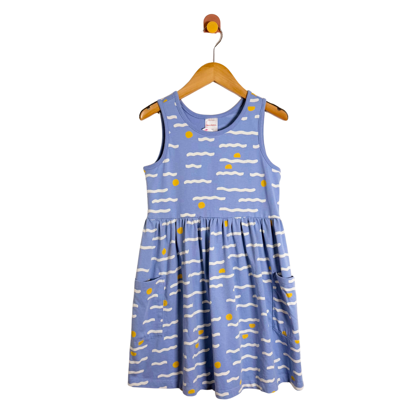 Blue dress with white and yellow patterns on a wooden hanger against a white background