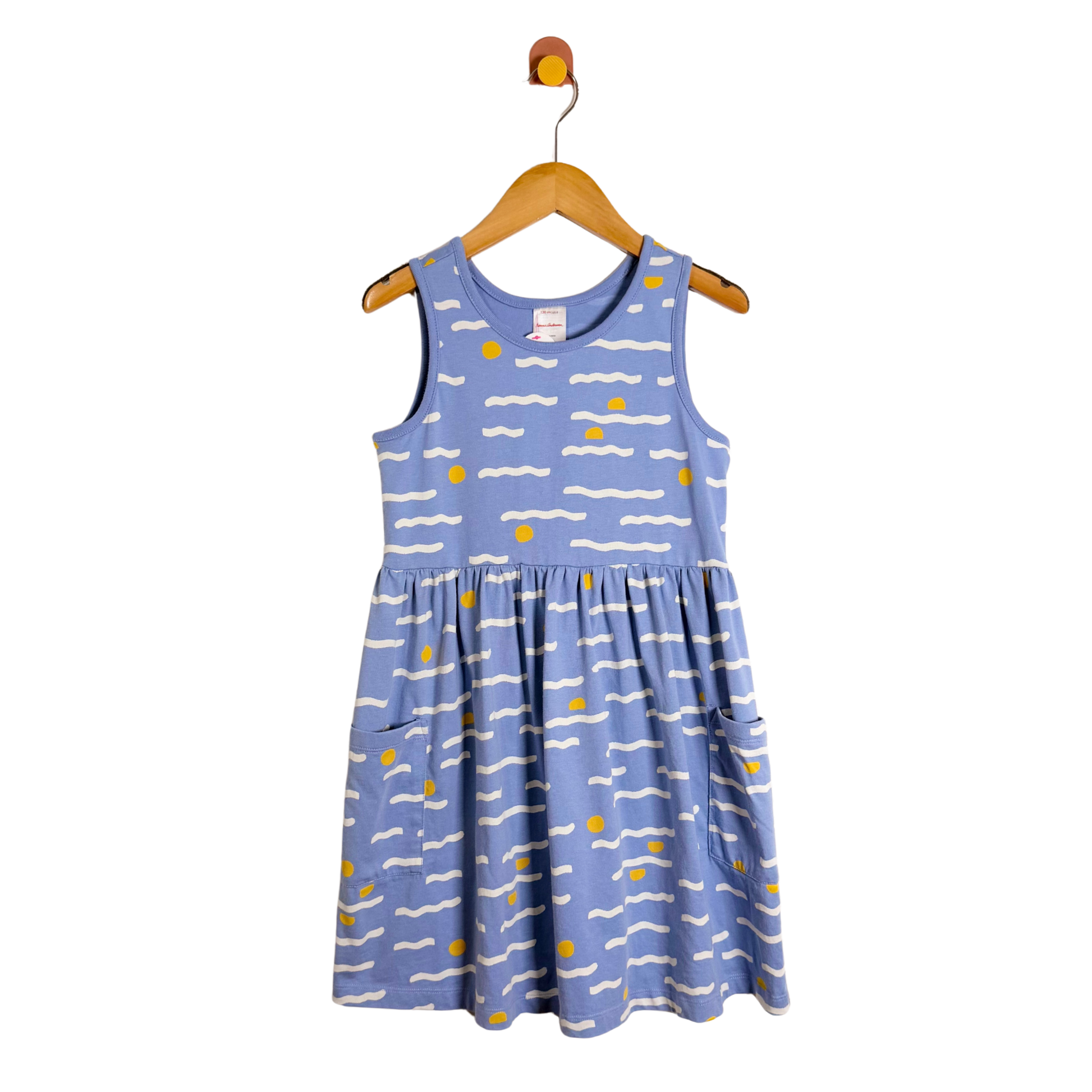 Blue dress with white and yellow patterns on a wooden hanger against a white background