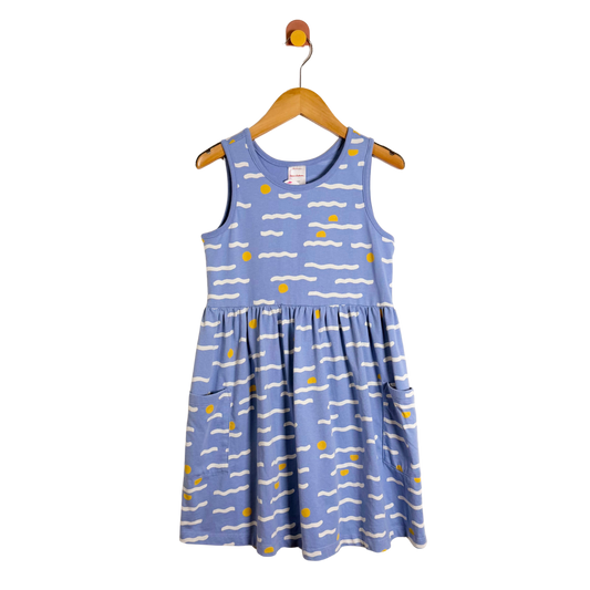 Blue dress with white and yellow patterns on a wooden hanger against a white background