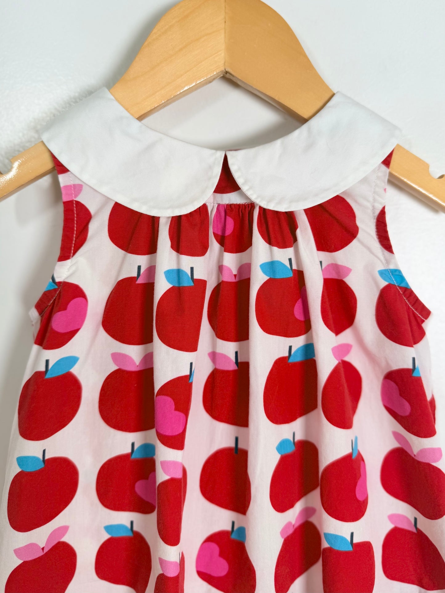 Children's dress with red apple pattern on a hanger