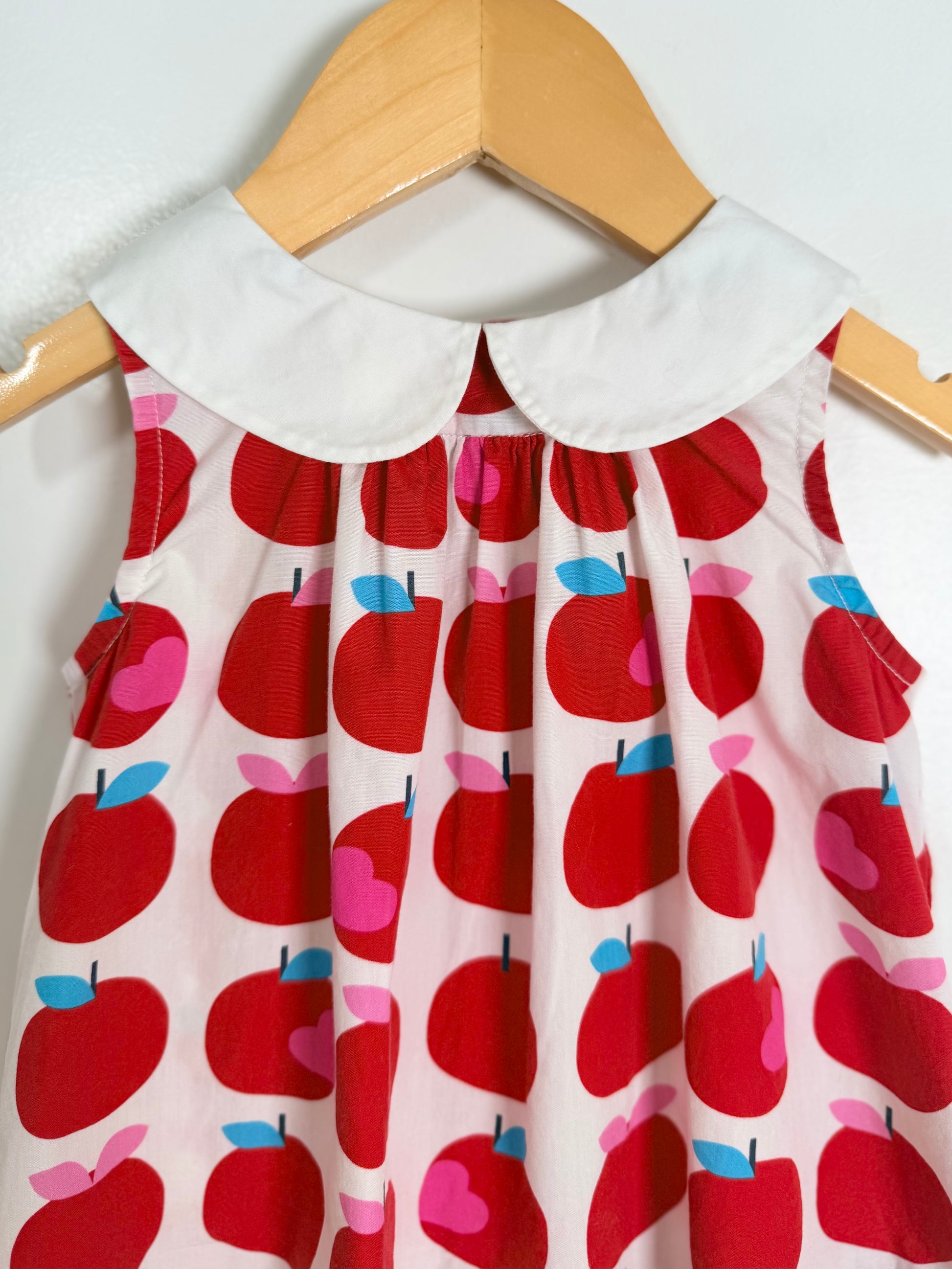 Children's dress with red apple pattern on a hanger