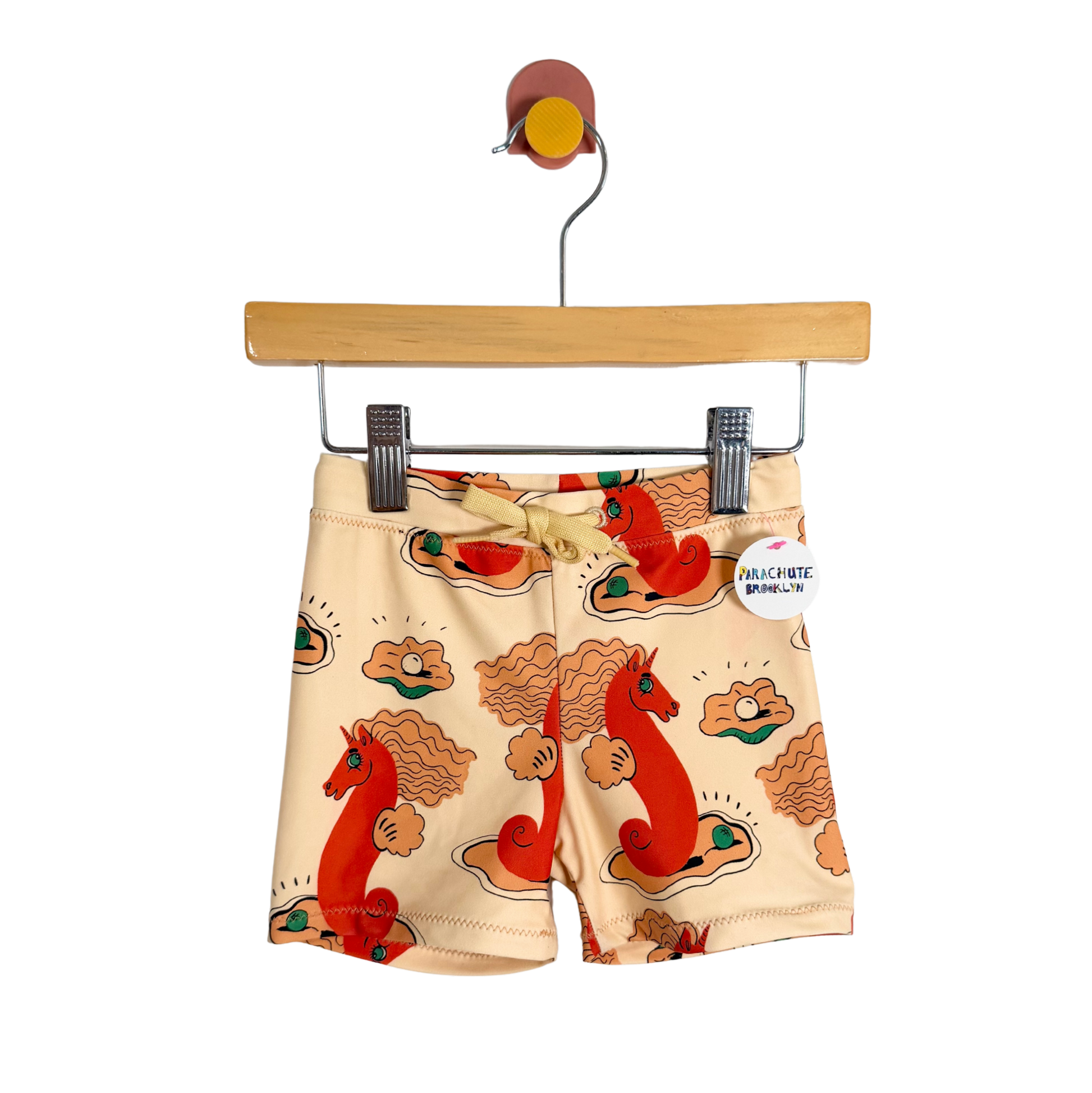 Children's shorts with a horse pattern on a hanger against a white background