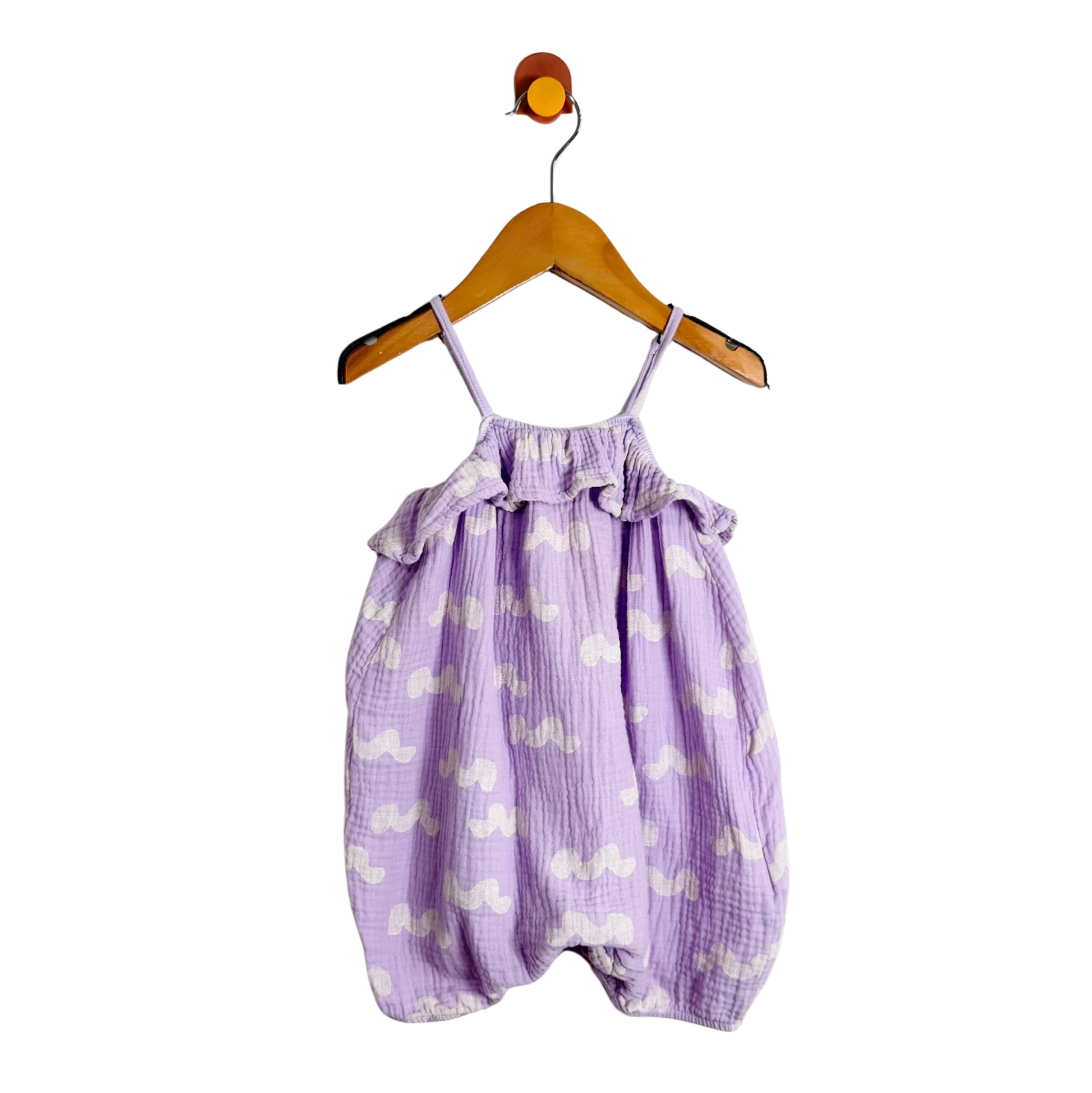Purple baby romper with white patterns on a wooden hanger against a white background
