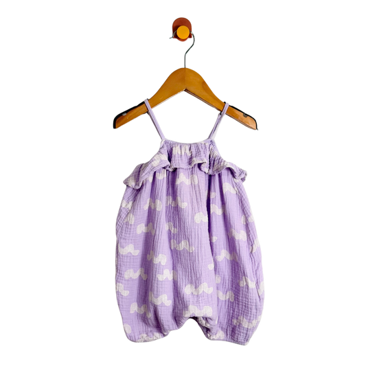 Purple baby romper with white patterns on a wooden hanger against a white background