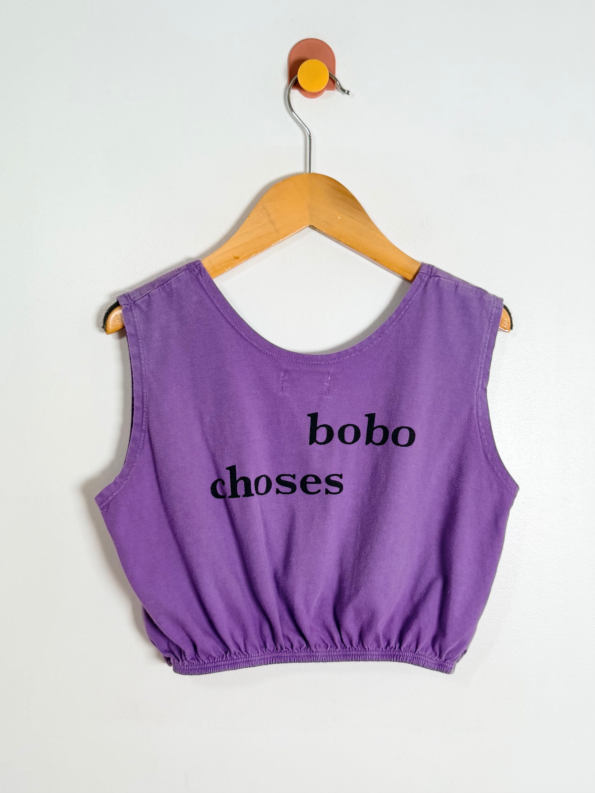 Purple tank top with 'bobochoses' text on a wooden hanger against a white background