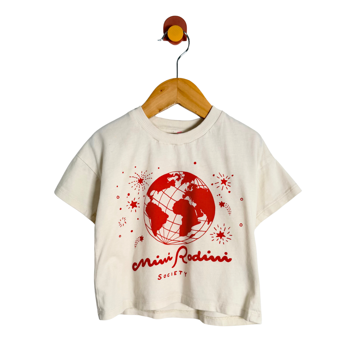 Beige t-shirt with red graphic and text on a wooden hanger against a white background