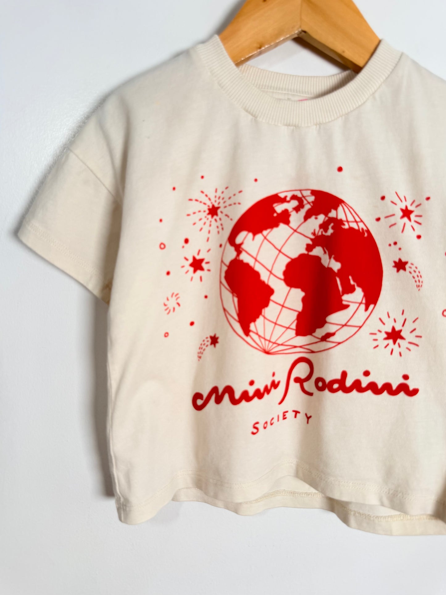 Beige t-shirt with red globe design and text on a white background