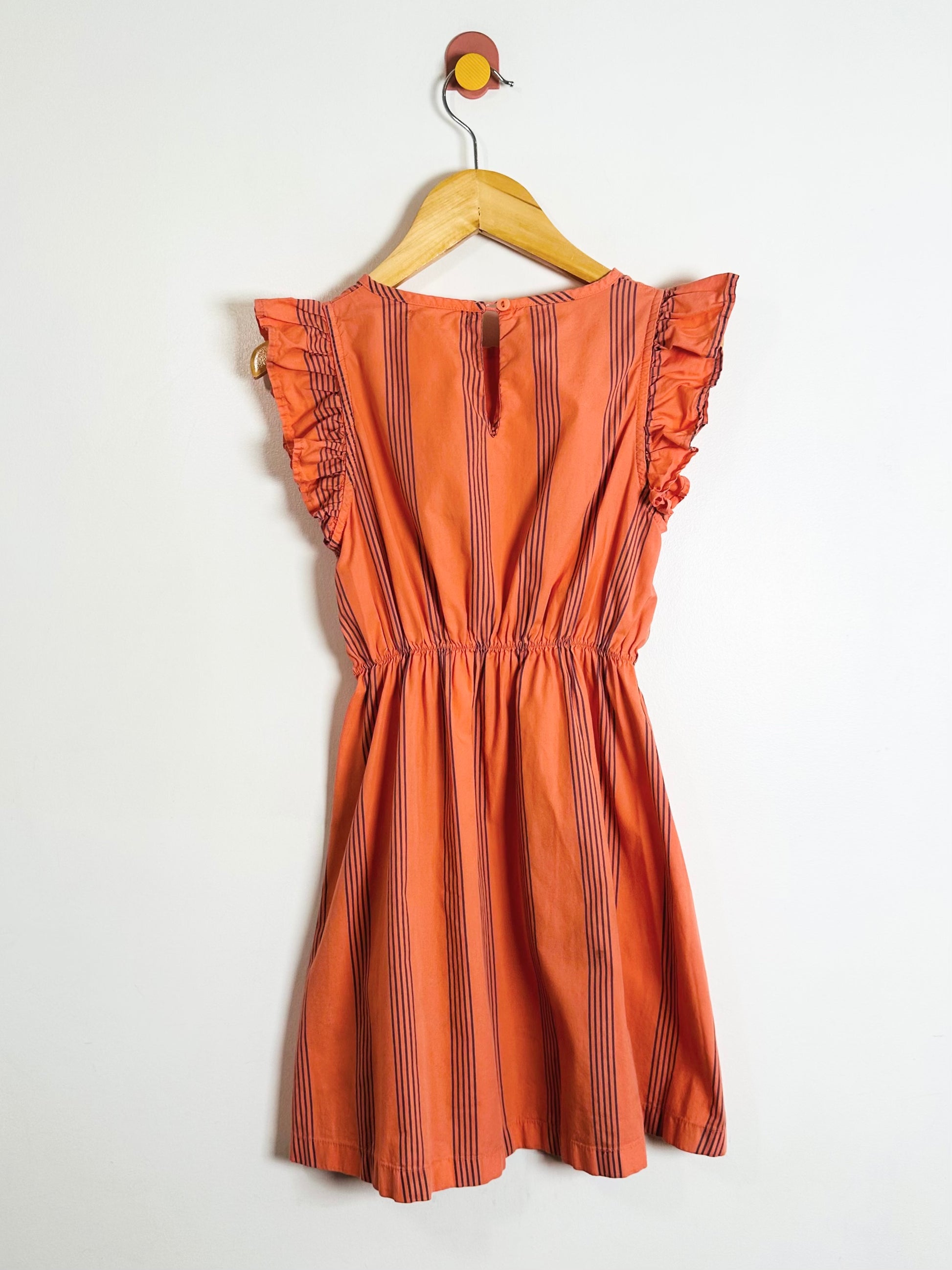 Orange striped dress on a hanger against a white background