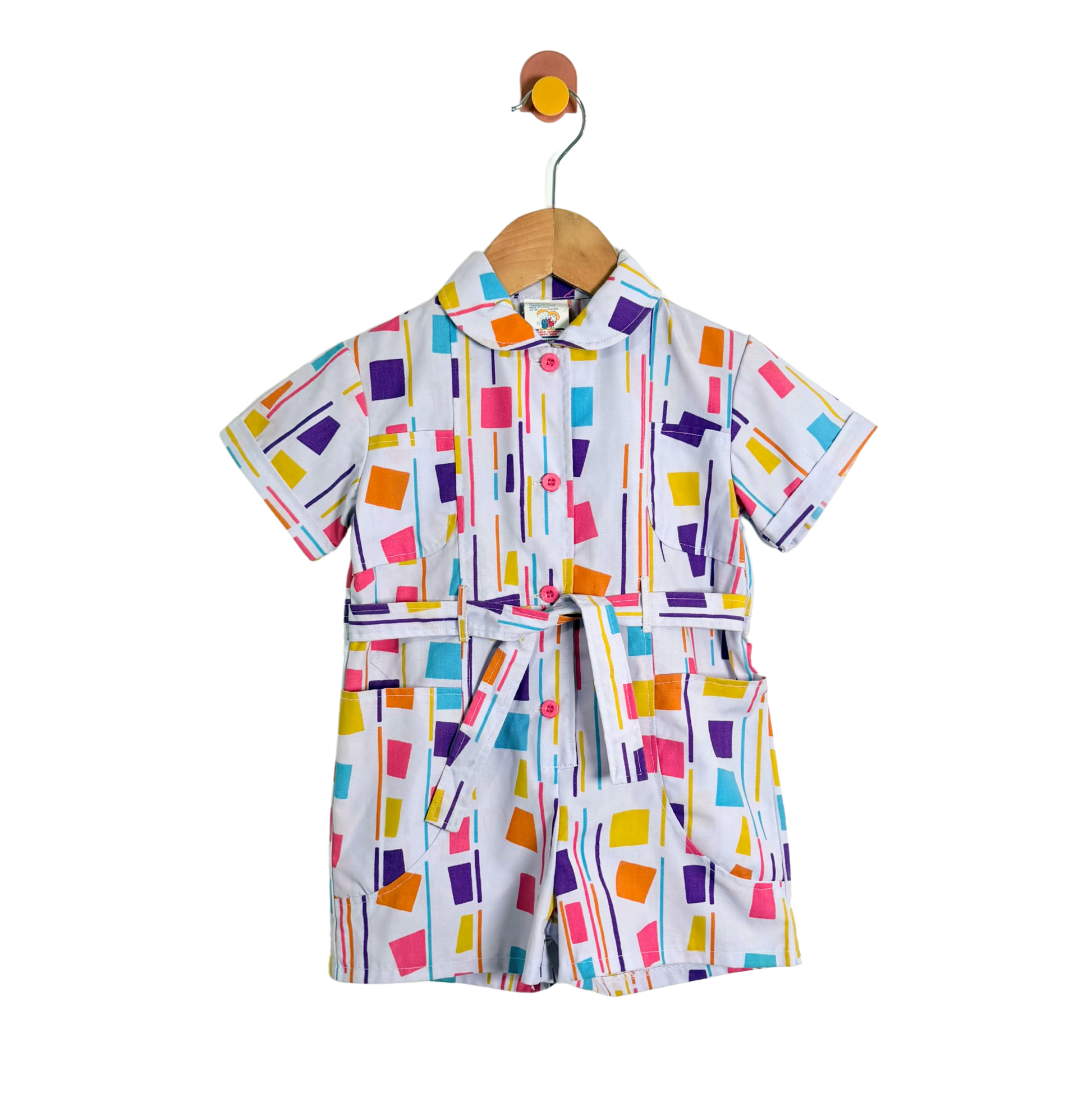 Colorful geometric patterned outfit on a hanger against a white background
