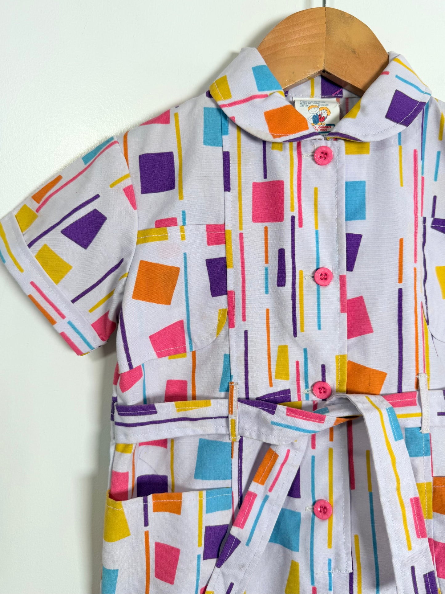 Colorful geometric patterned shirt on a wooden hanger against a white background