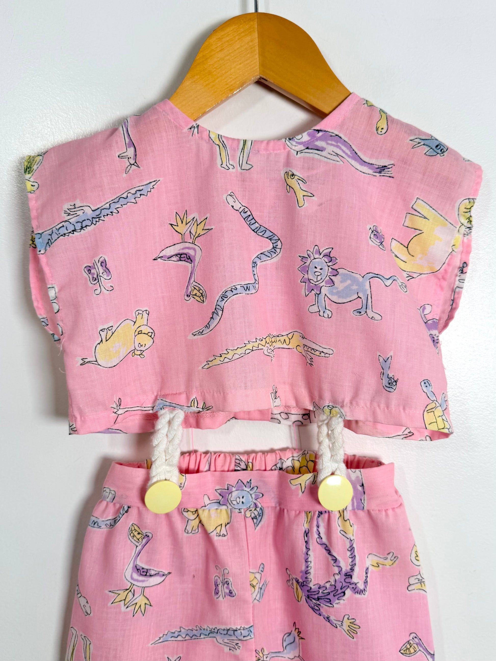 Pink children's outfit with animal print on a hanger against a white background