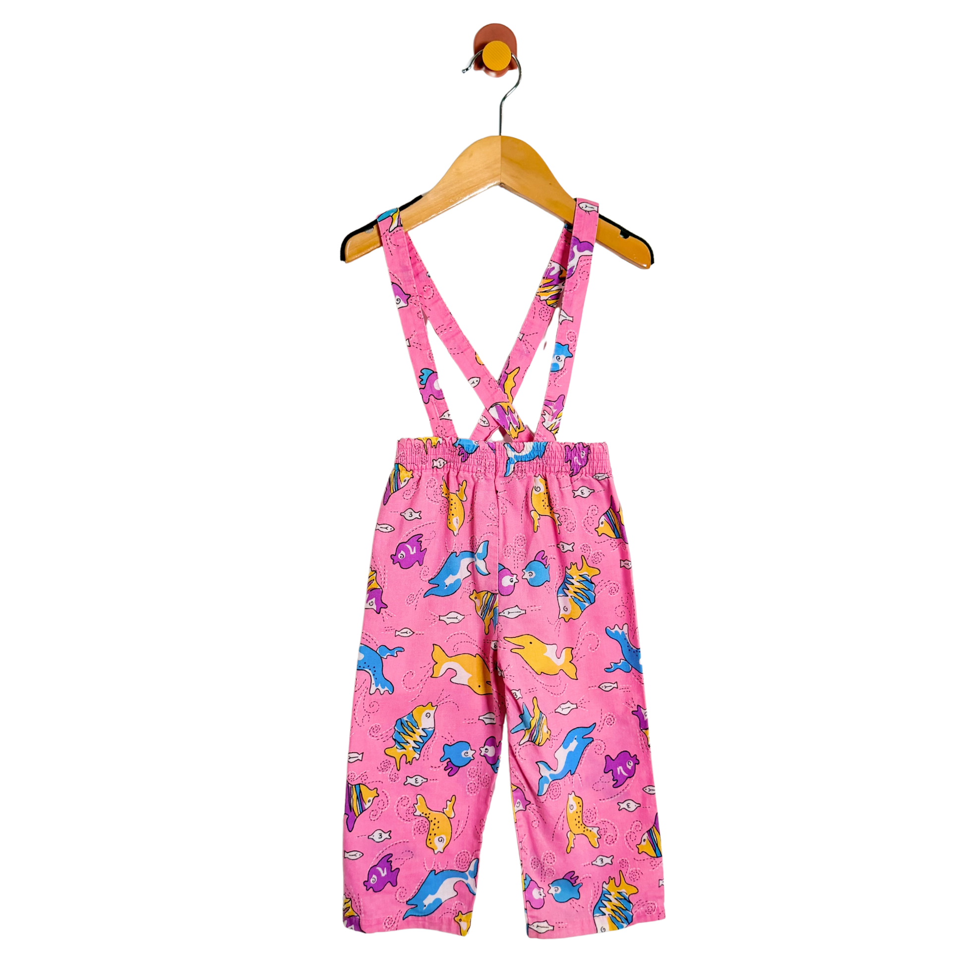 Pink children's overalls with animal pattern on a hanger against a white background
