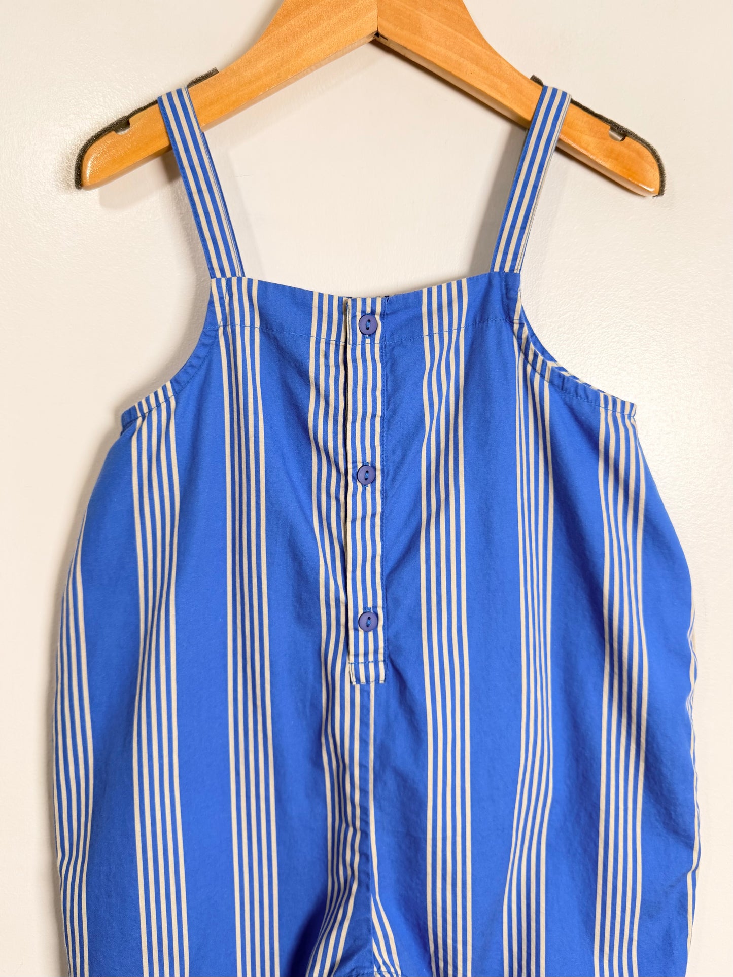 Blue and white striped romper on a wooden hanger against a white background