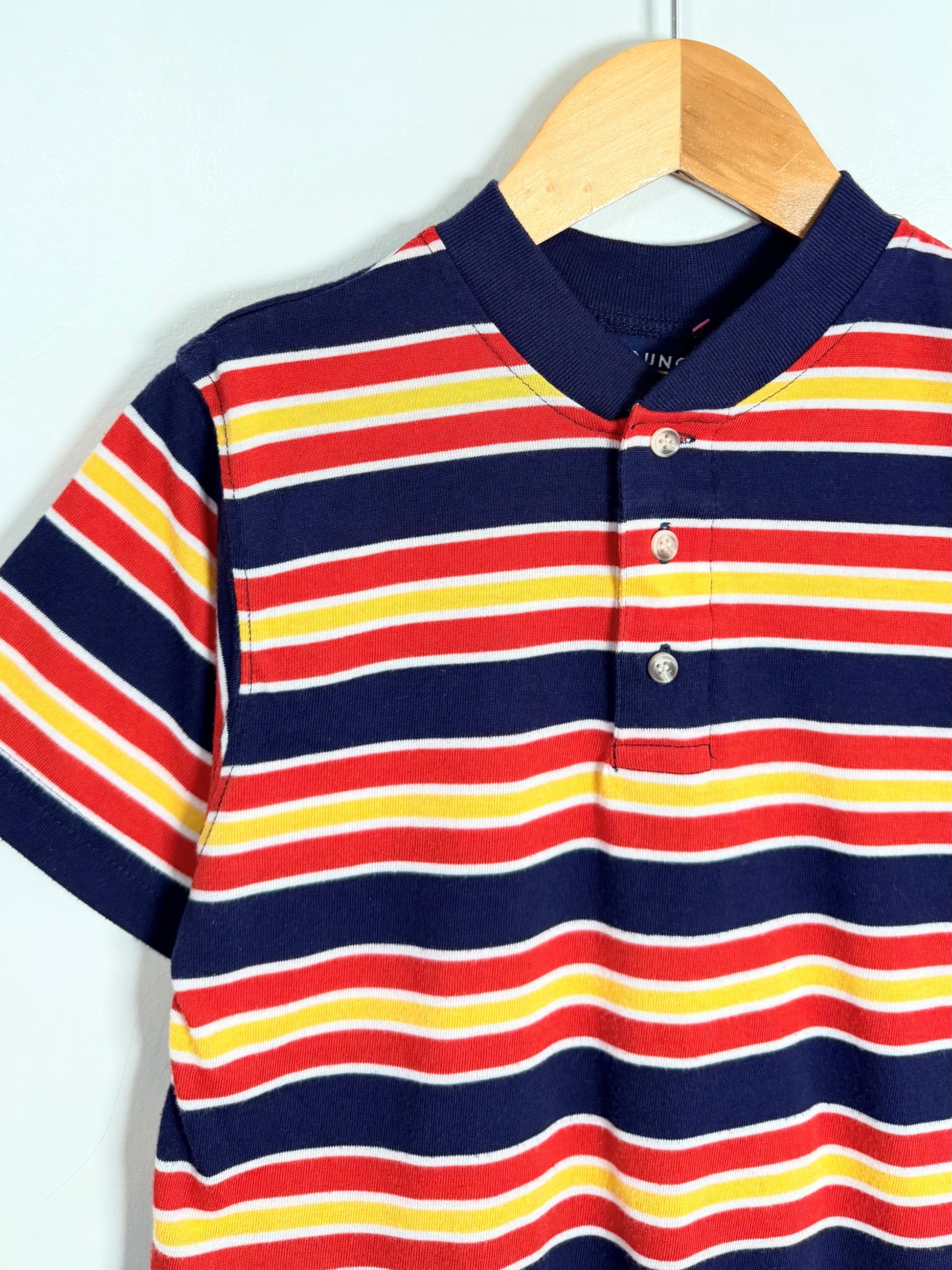 Striped polo shirt with red, yellow, and blue stripes on a hanger against a white background