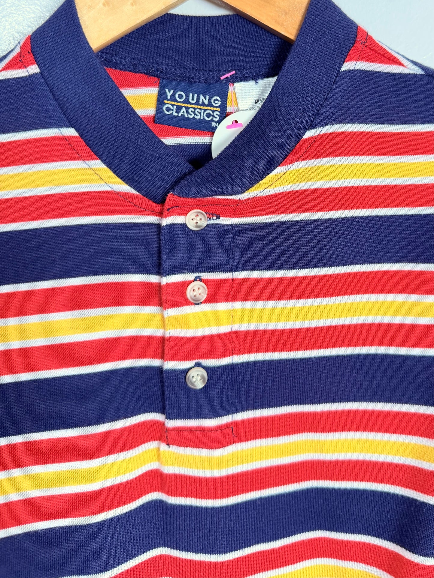 Striped polo shirt with red, yellow, and blue horizontal stripes on a hanger.